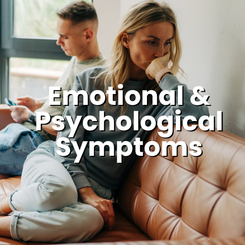 A woman sitting on a couch, looking distressed and thoughtful, with a young man in the background looking at his phone, in a room with a window.