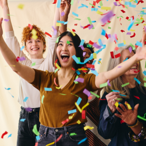 People celebrating with colorful confetti and smiling brightly.