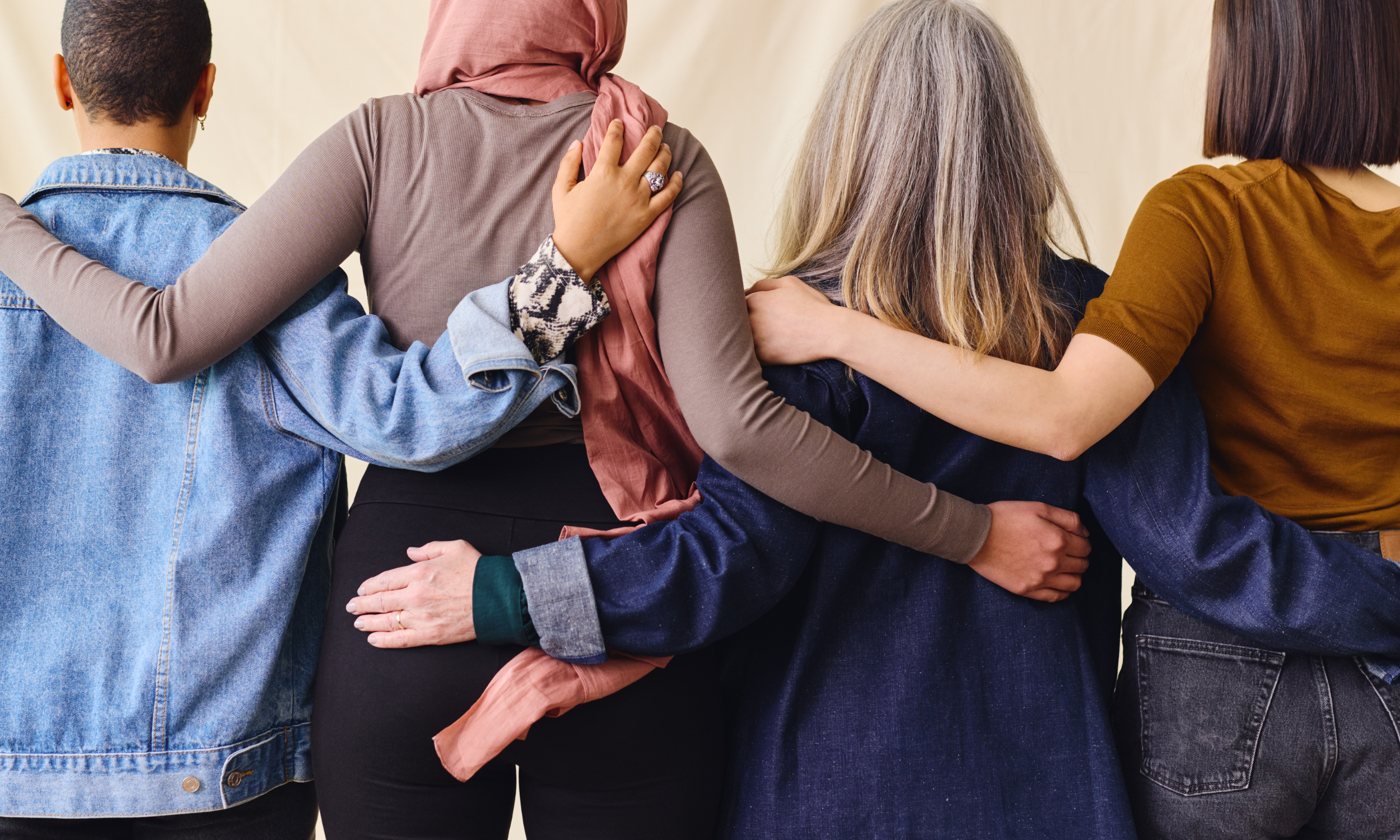 Group of diverse women with their arms around each other, standing together.