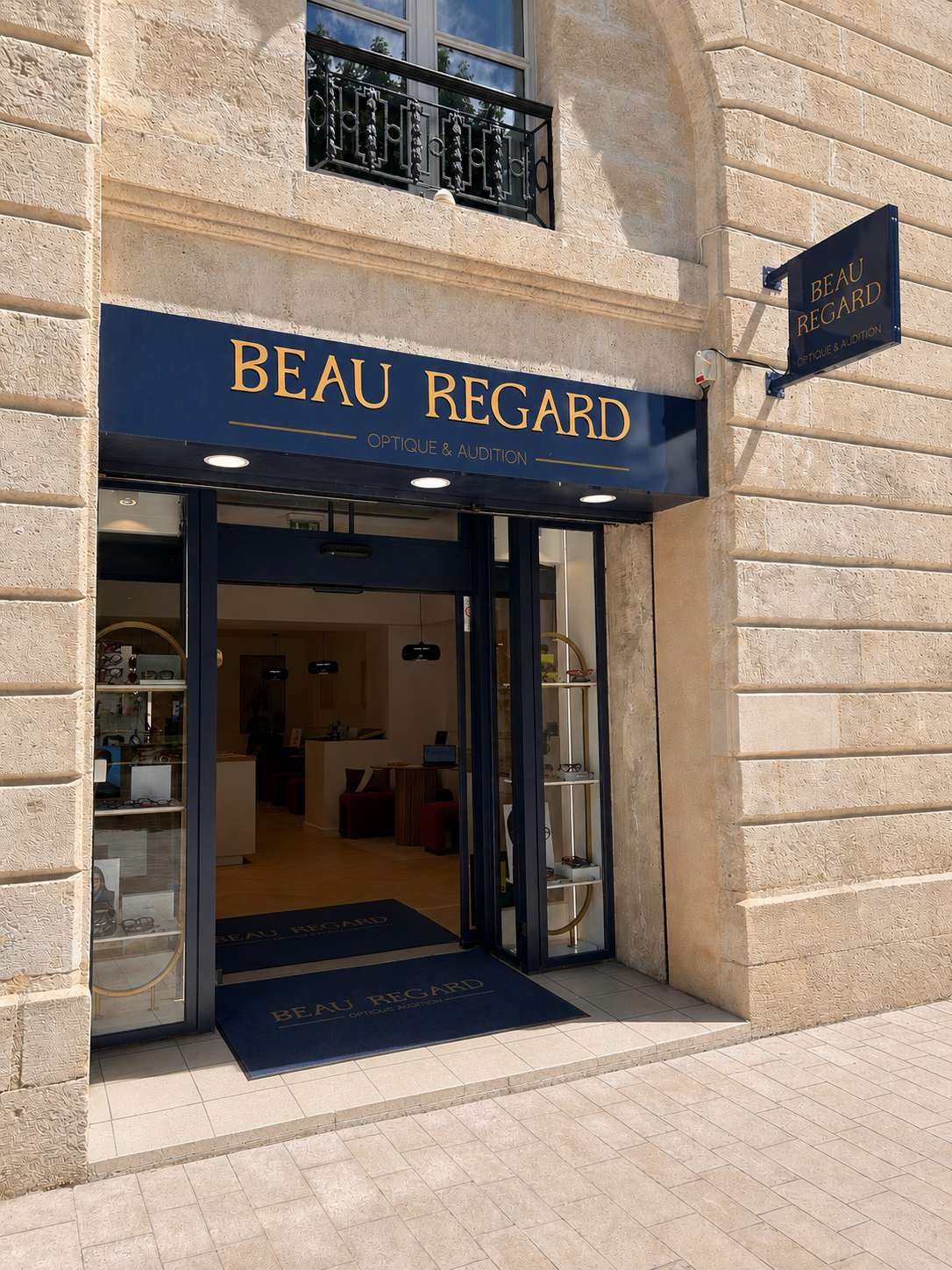Façade d'un magasin optique nommé BEAU REGARD, avec une enseigne bleue avec lettres jaunes, vitres sur les côtés affichant des produits, et une porte en verre. place gambetta bordeaux