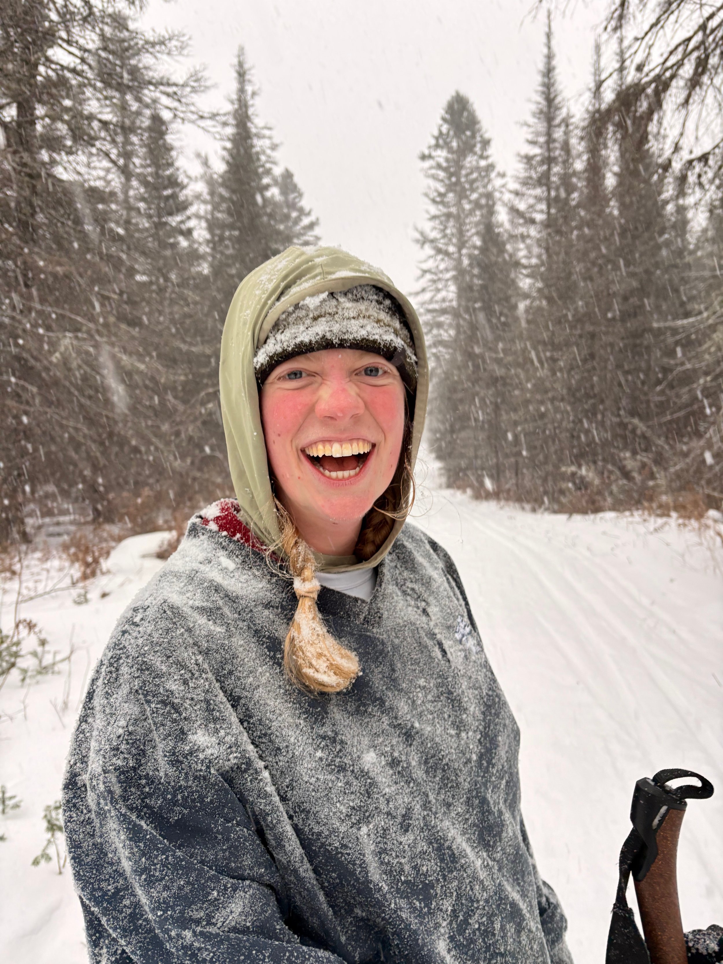 Portrait of a smiling man in a blue blazer and light blue shirt outdoors with a blurred green background.