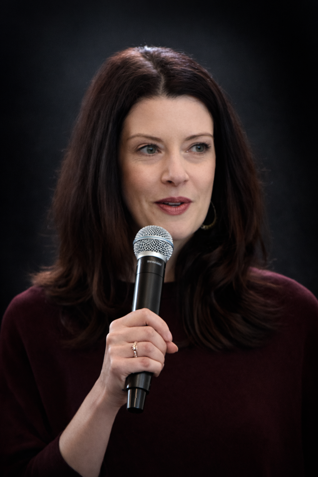 Woman with curly black hair wearing a yellow pantsuit and white sneakers, sitting on a yellow floor against a yellow background.