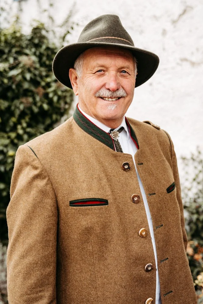 Schatten einer Person vor weißem Hintergrund, Person trägt einen dunklen Mantel, Gesicht nicht sichtbar.