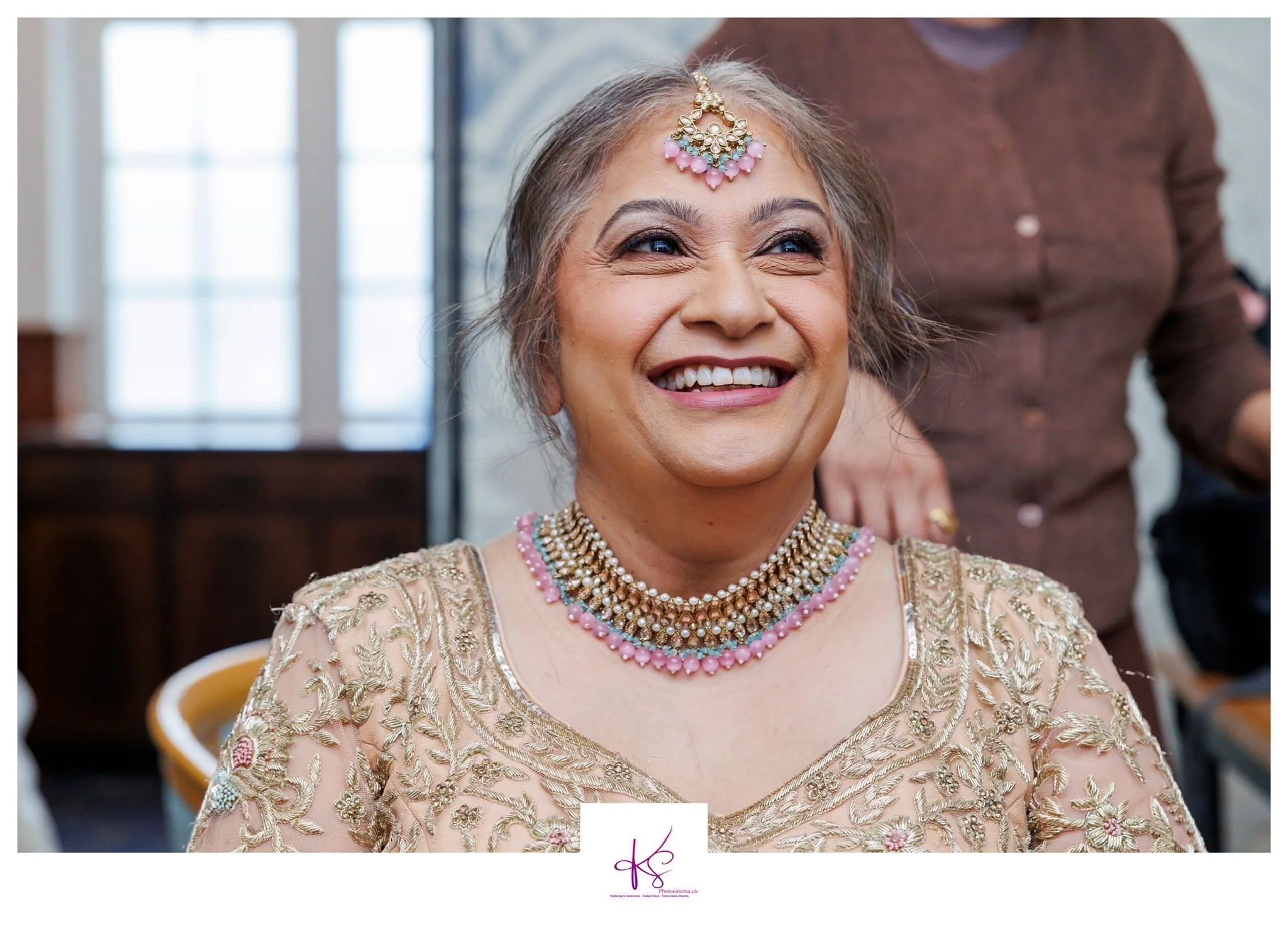 Woman in gold and pink indian jewellery with Indian outfit smiling after getting makeup done for renewal of vows ceremony