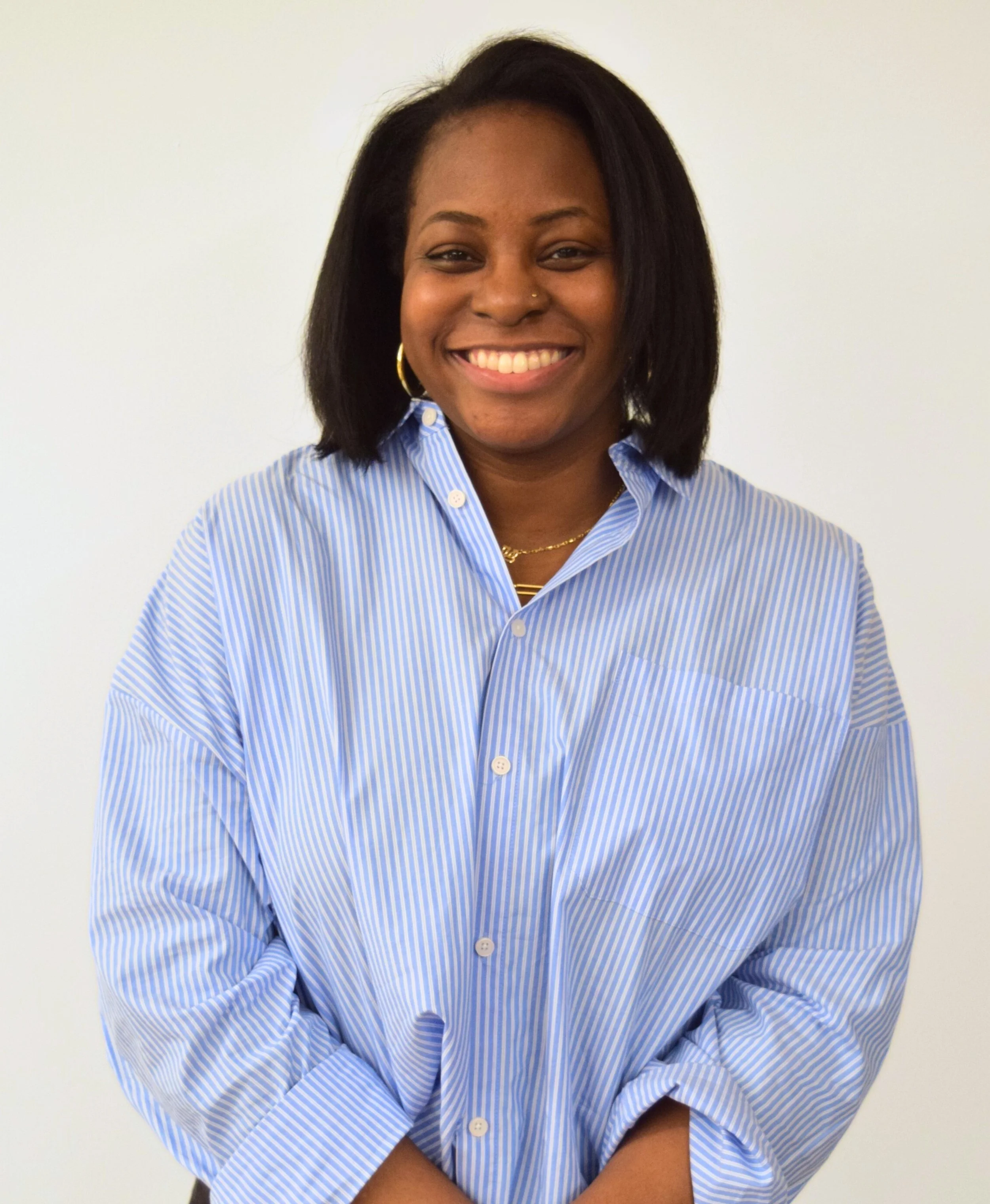 A Black woman with straight shoulder length hair wearing a light blue button-up shirt