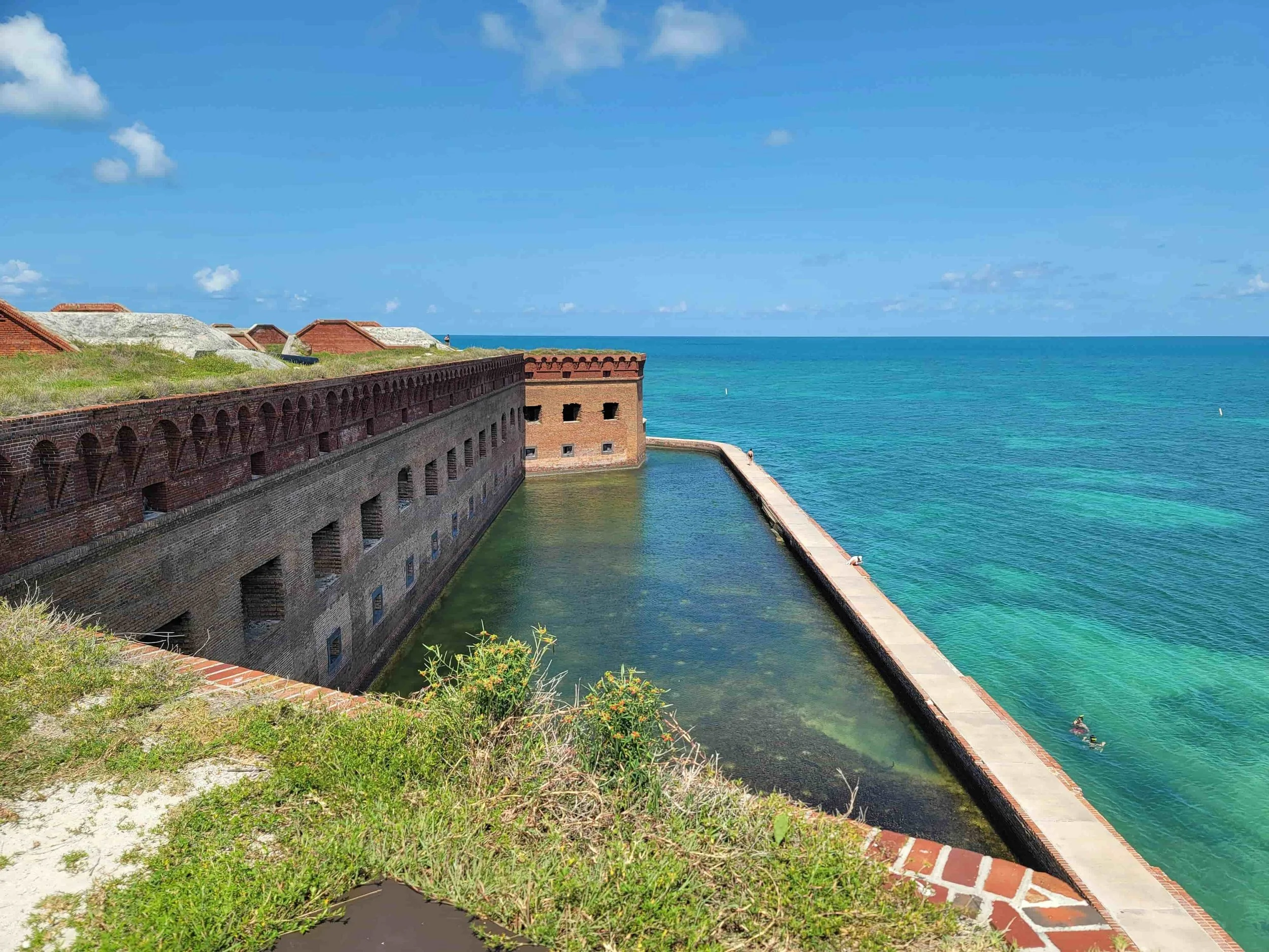 Image of Fort Jefferson in the Dry Tortugas National Park. Blue waters, and blue skys with the exterior of the building going down into the ocean.