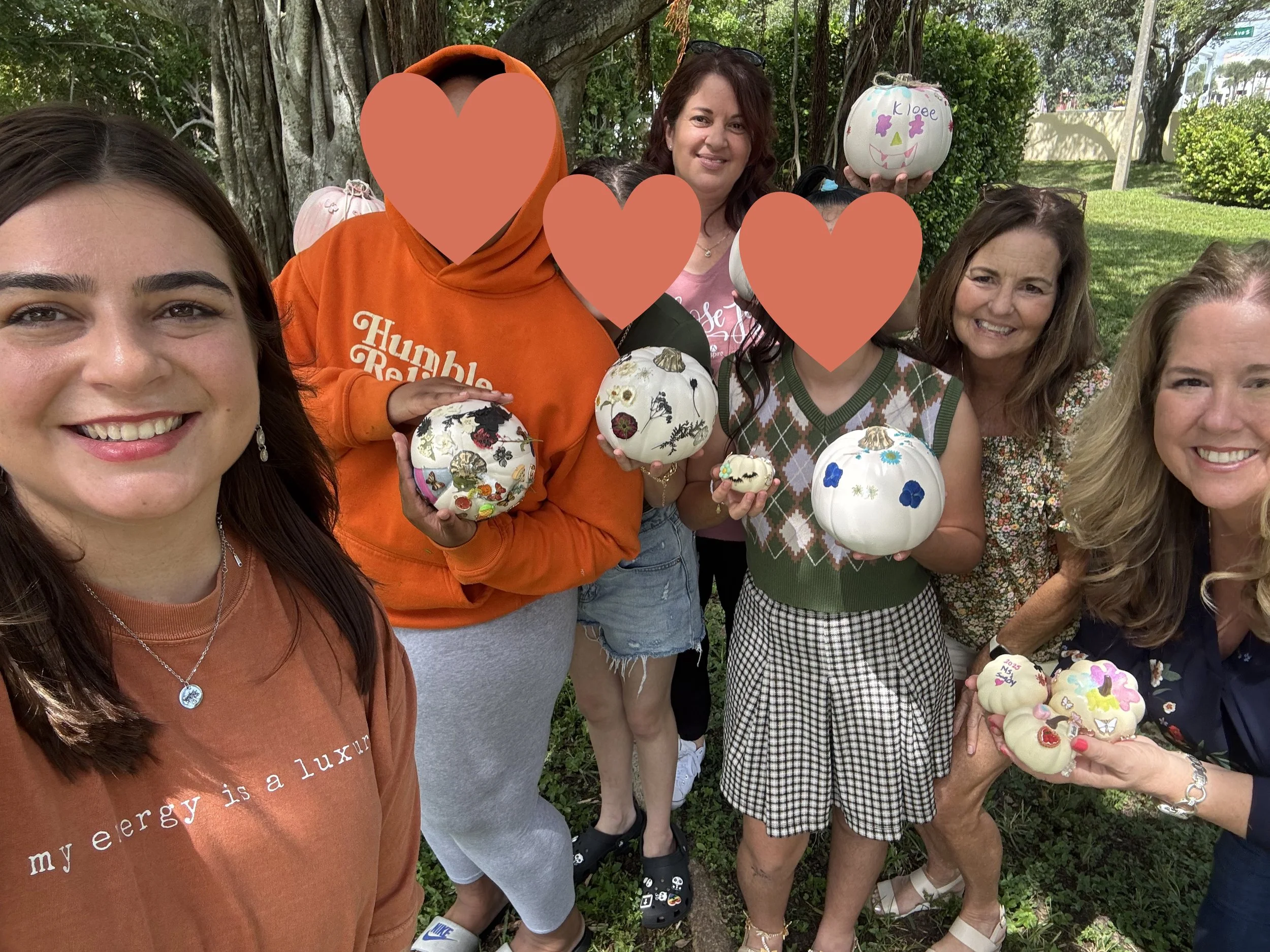 A group of  four volunteers with three Hearts of Hope foster youth holding pumpkins after a Day of Hope.