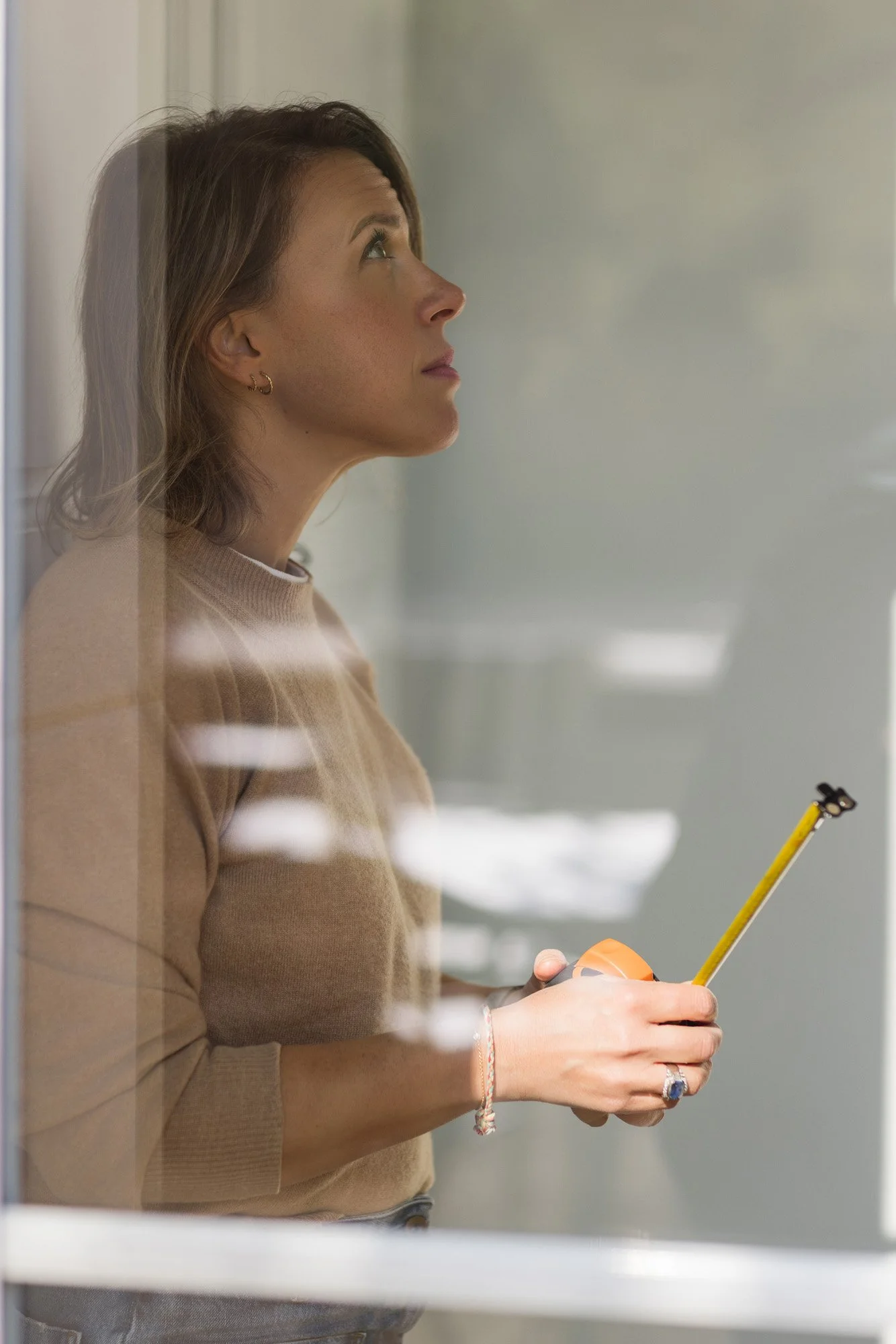 Mathilde Bigot femme 40 ans, se tient debout, un mètre ruban à la main, prête à mesurer un projet