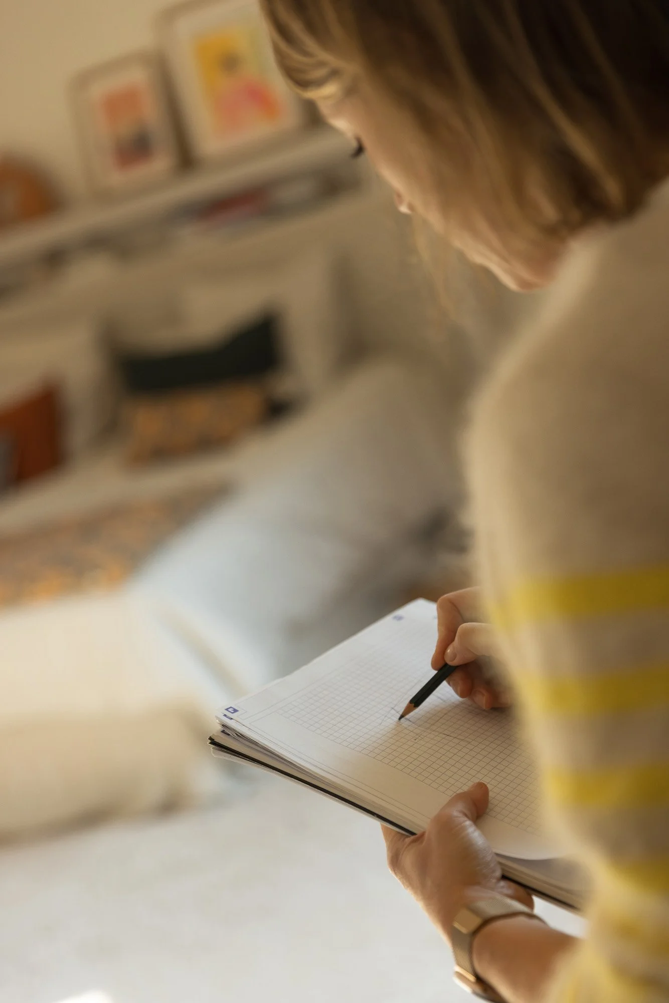 Mathilde Bigot se tient debout de dos et est en train de faire des esquisses sur un cahier