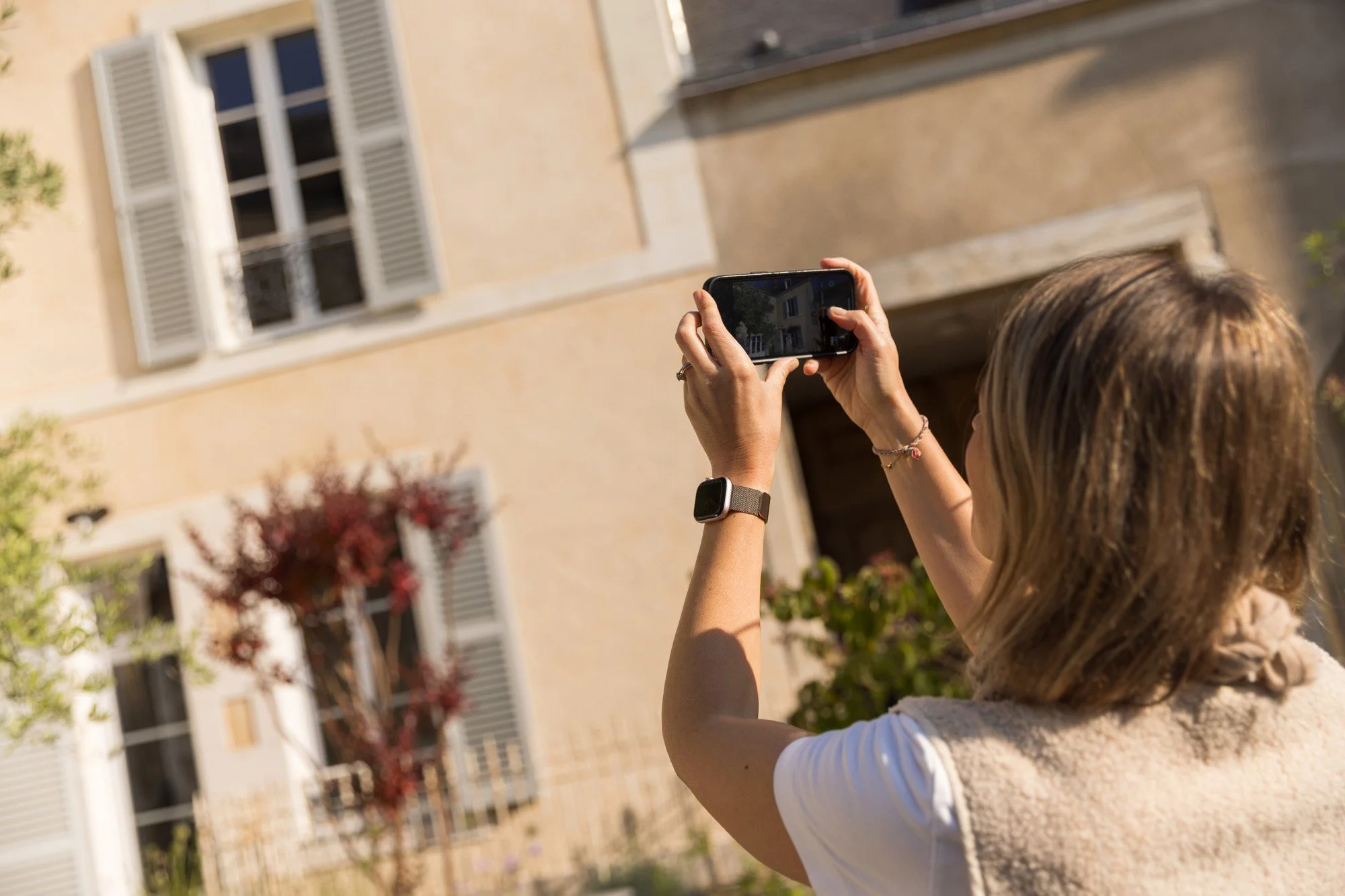Une femme prenant une photo ou un selfie avec un smartphone dans un environnement urbain en plein jour.
