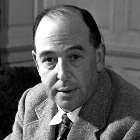 Black and white photo of a man in a suit and tie sitting indoors.