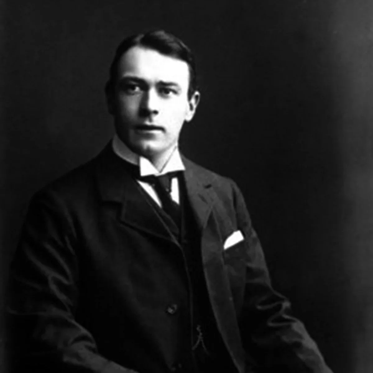 Black and white portrait of a young man in formal attire, including a jacket, vest, shirt, and tie.