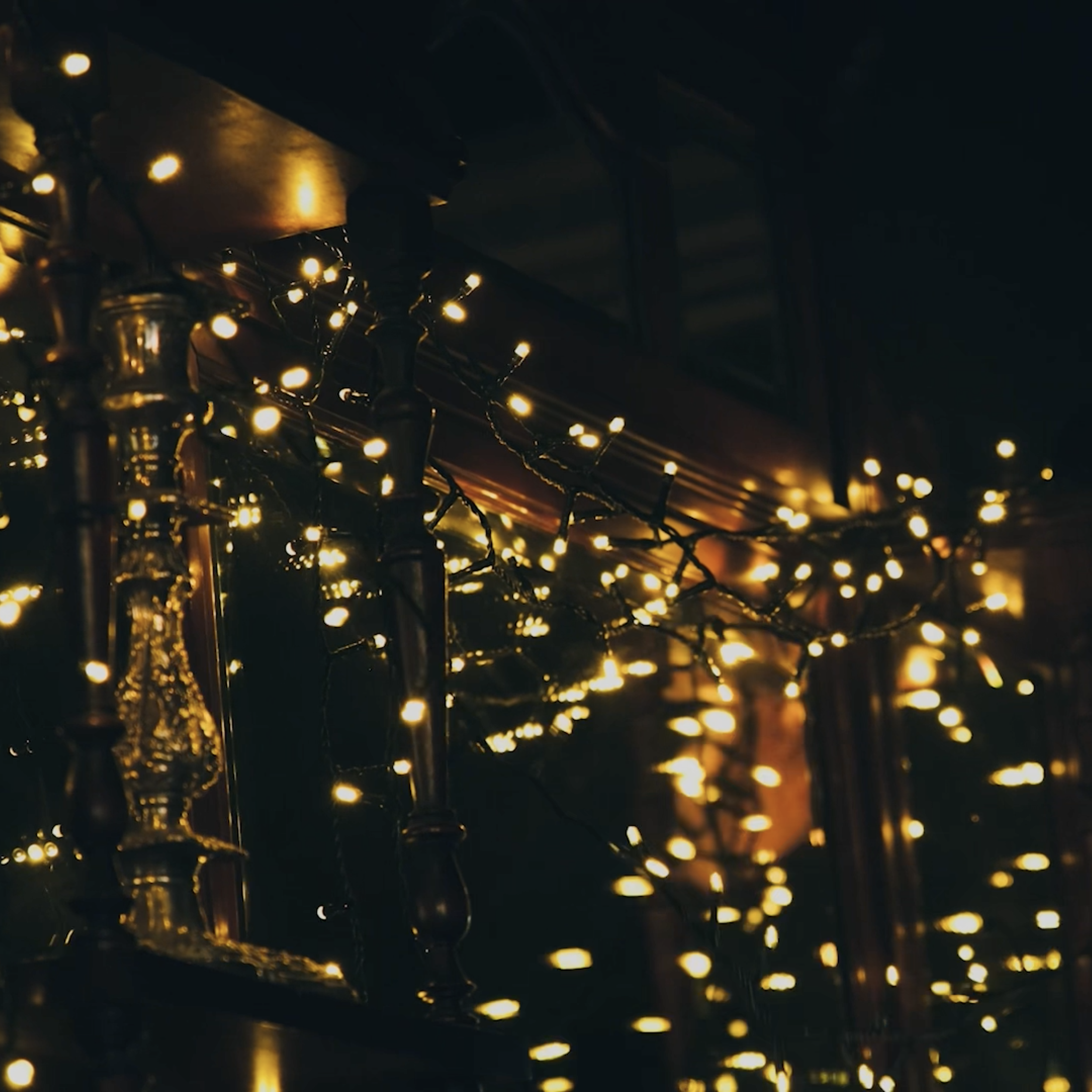 Close-up of warm yellow string lights hanging in a dark room, creating a cozy and festive atmosphere.