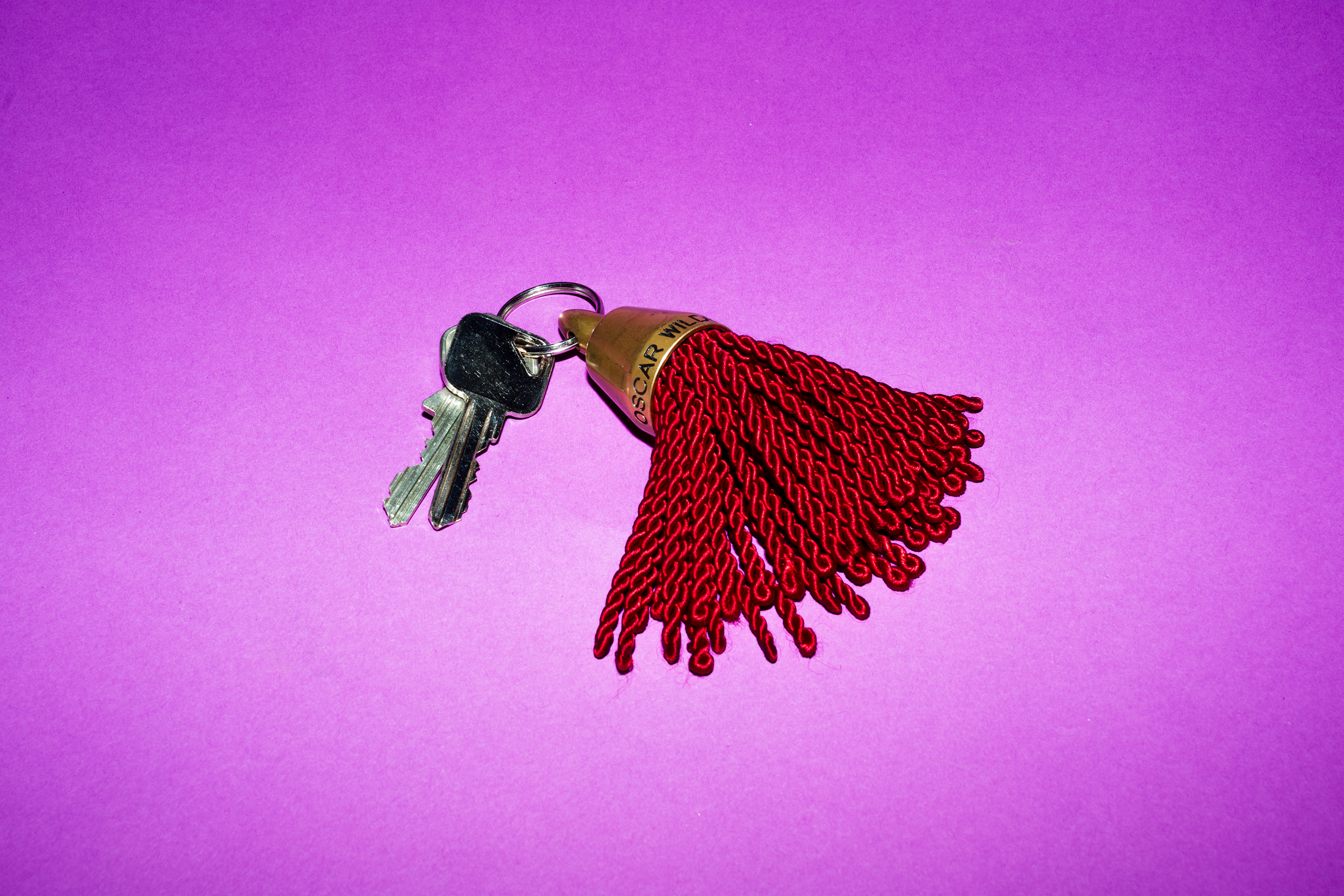 A set of keys on a purple background with a red tassel attached.