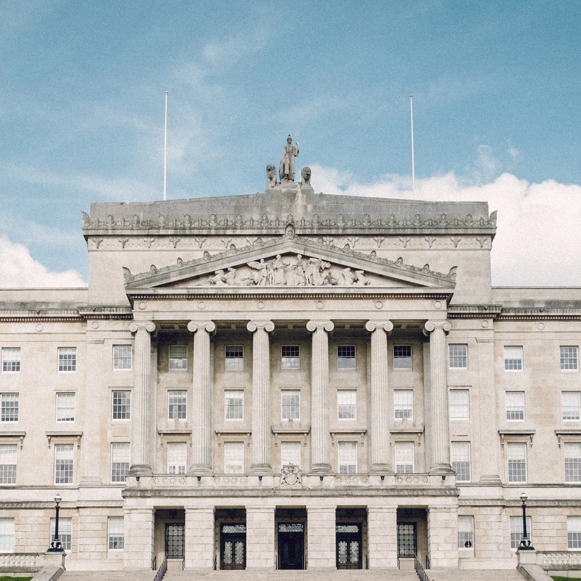A neoclassical government building with columns, statues, and classical architectural details.