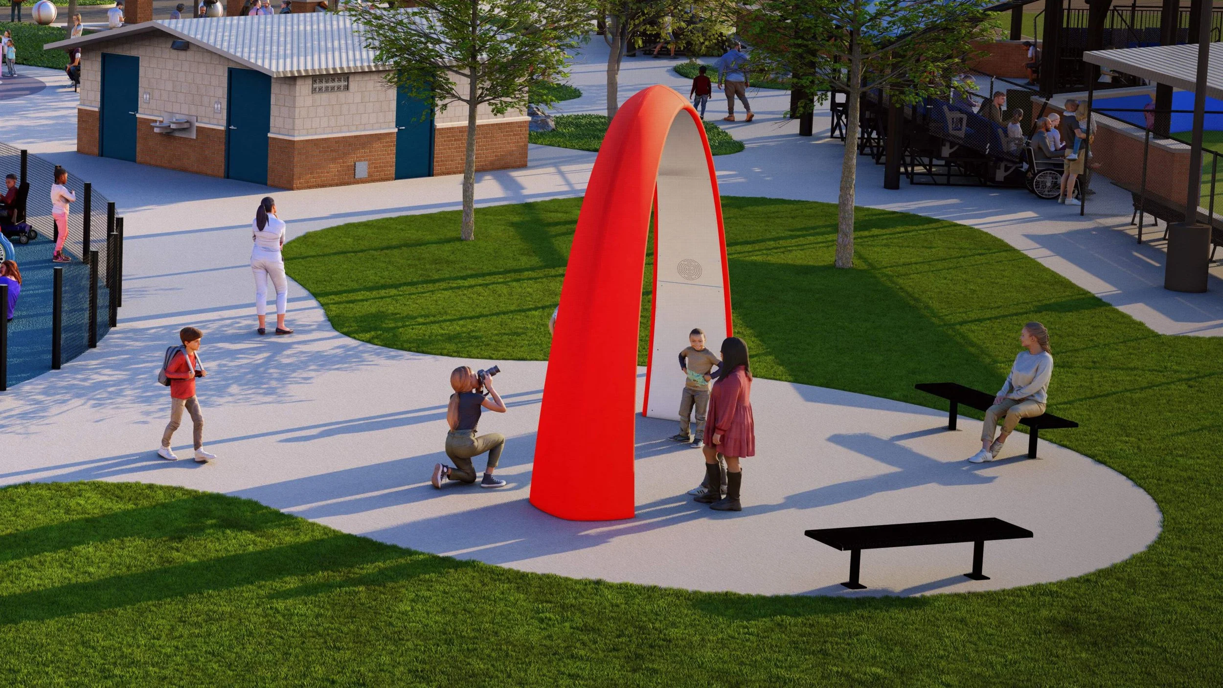 A playground with a red, curved climbing structure in the center. Children are playing, some standing near the structure, a photographer taking pictures, and adults supervising. There are benches, trees, a small pavilion, and a fenced area with more kids in the background.