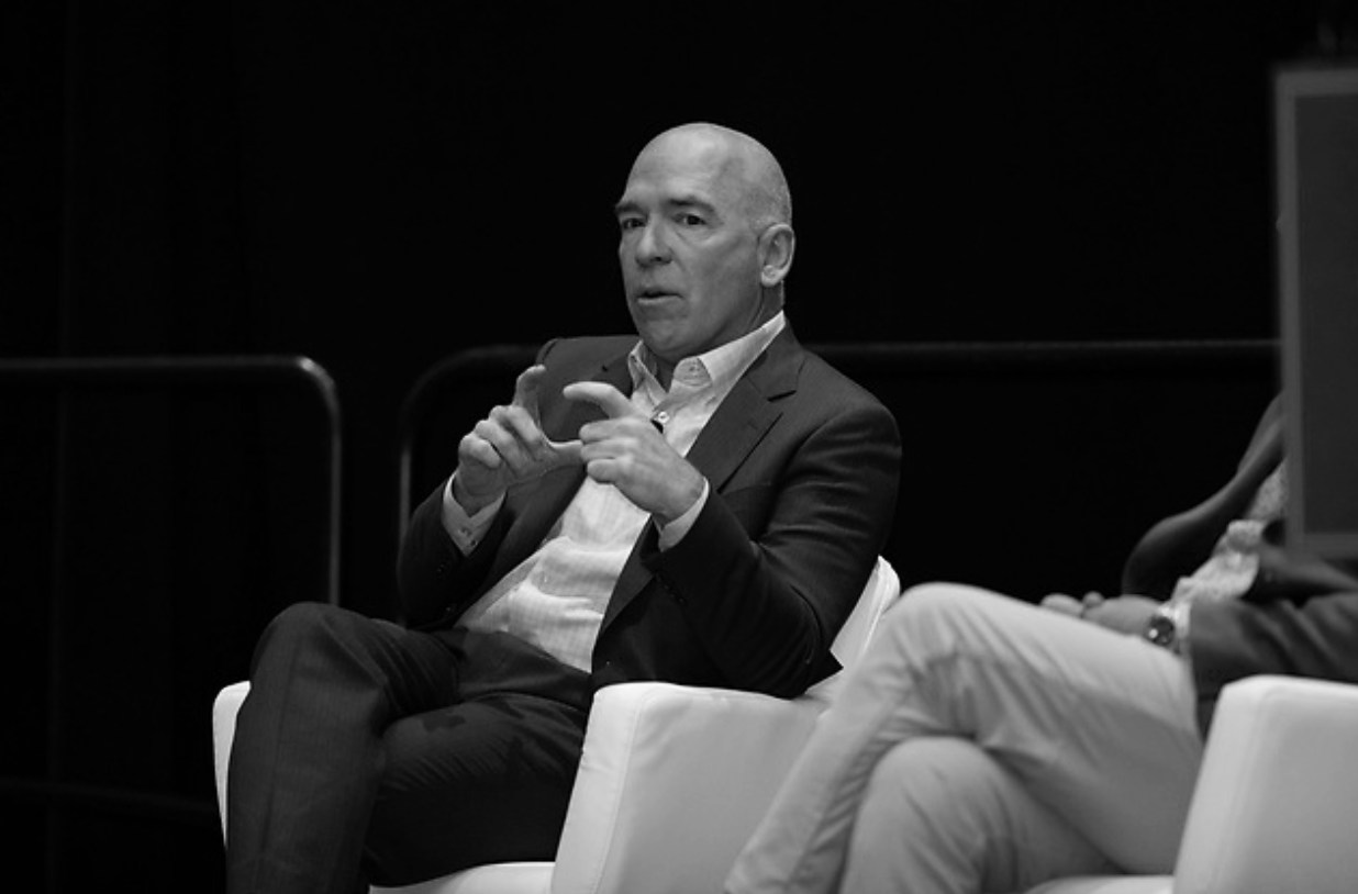 A man in a suit speaking during a panel discussion.