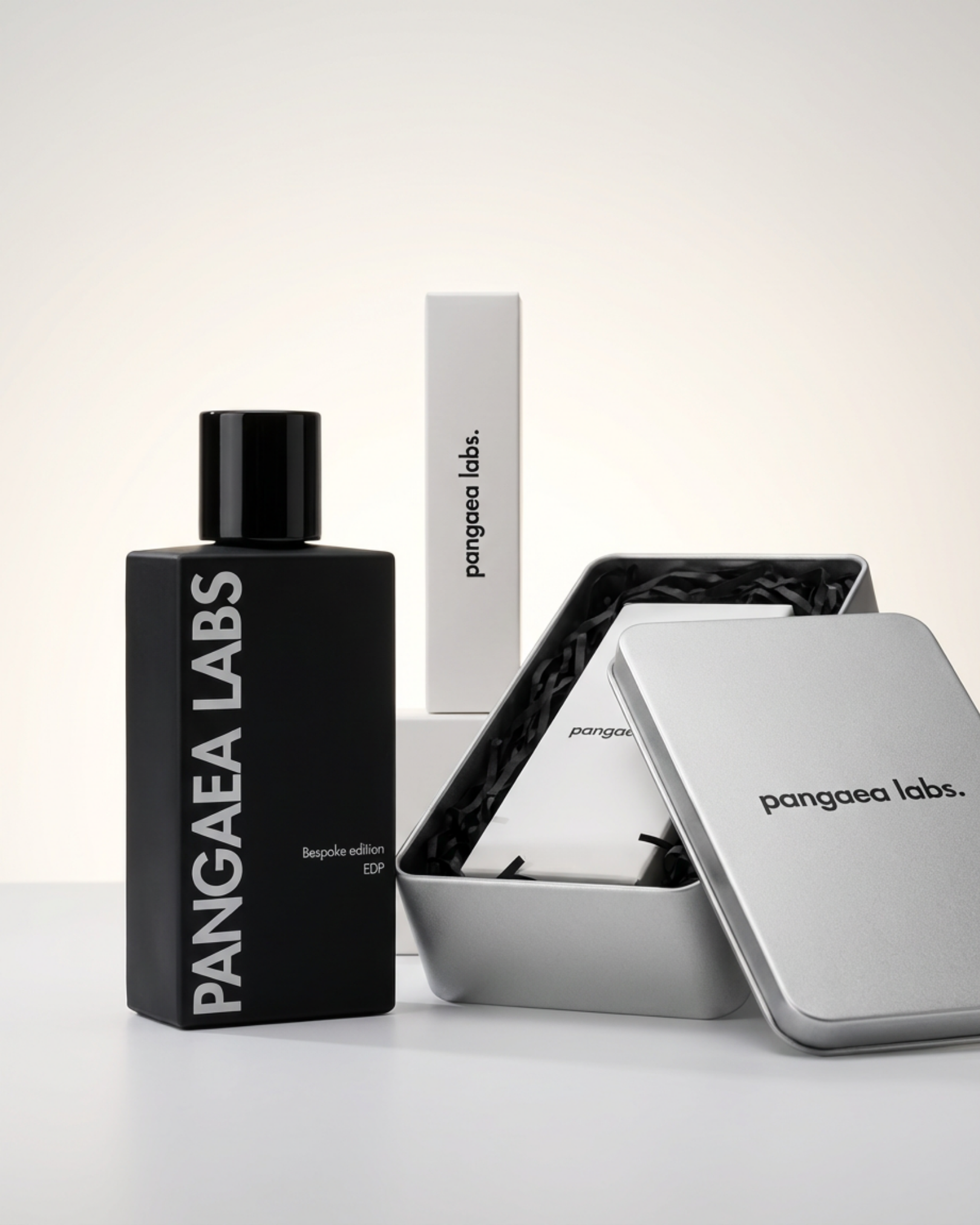 A collection of Pangaea Labs skincare products, including a black bottle, a white box, and a silver tin box, all with minimalist black and white branding, displayed on a white surface.