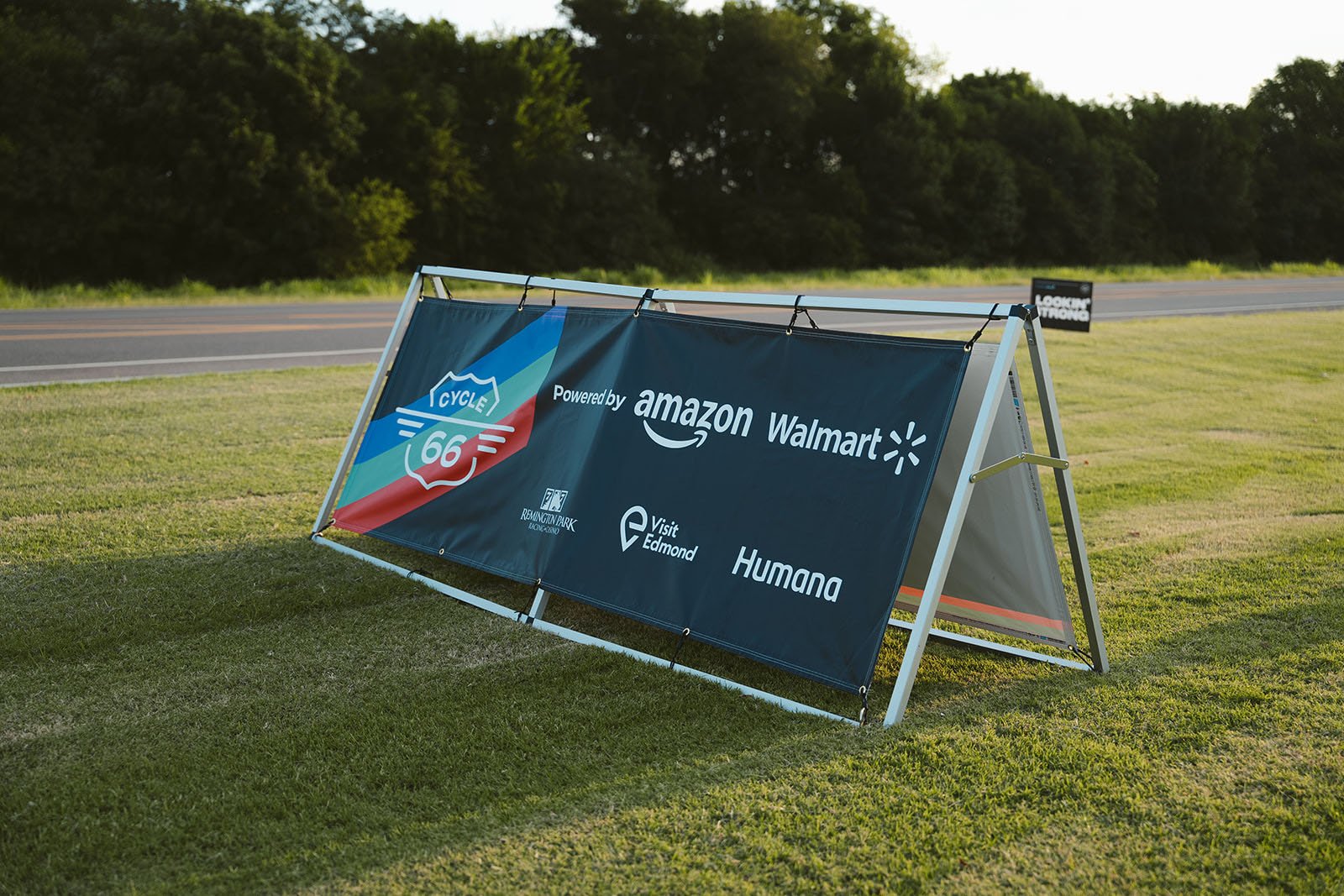 A roadside sign advertising a partnership between Amazon, Walmart, and other companies, with logos for Route 66 and Reuning Park.
