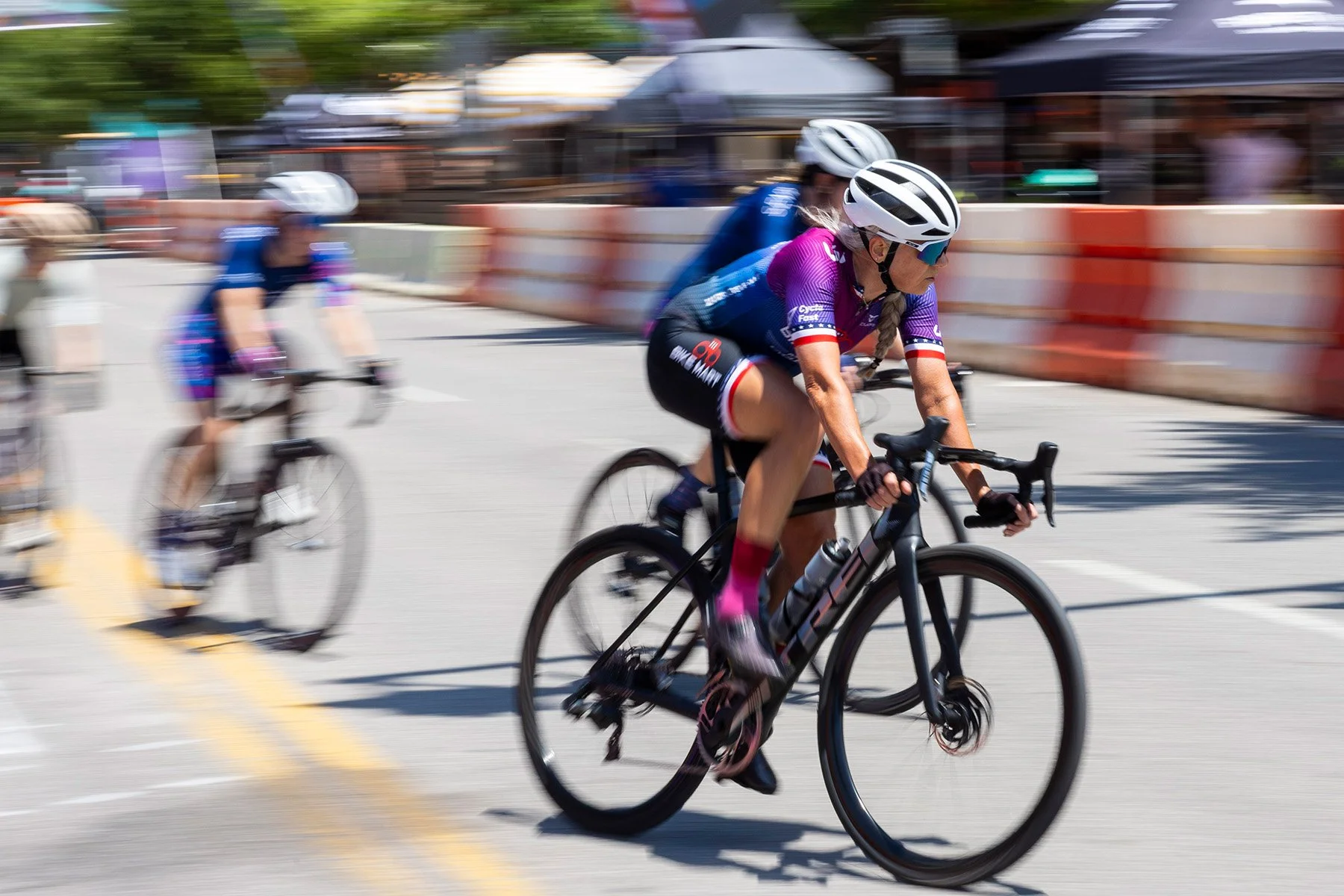 Cyclists racing on a city street during a bicycle race with colorful barriers and blurred background