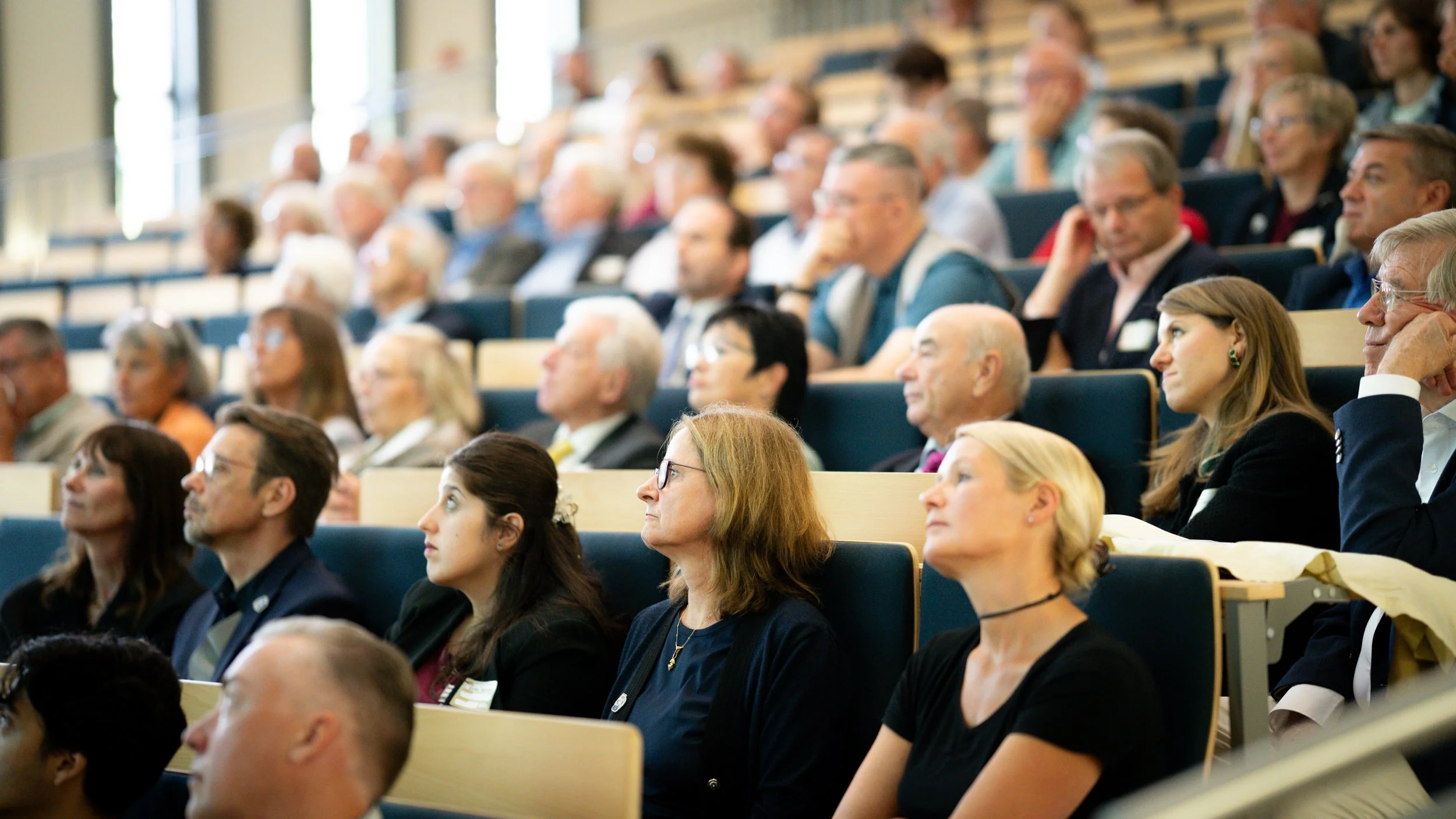 Erwachsene bei einer Konferenz, die aufmerksam auf eine Präsentation schauen.