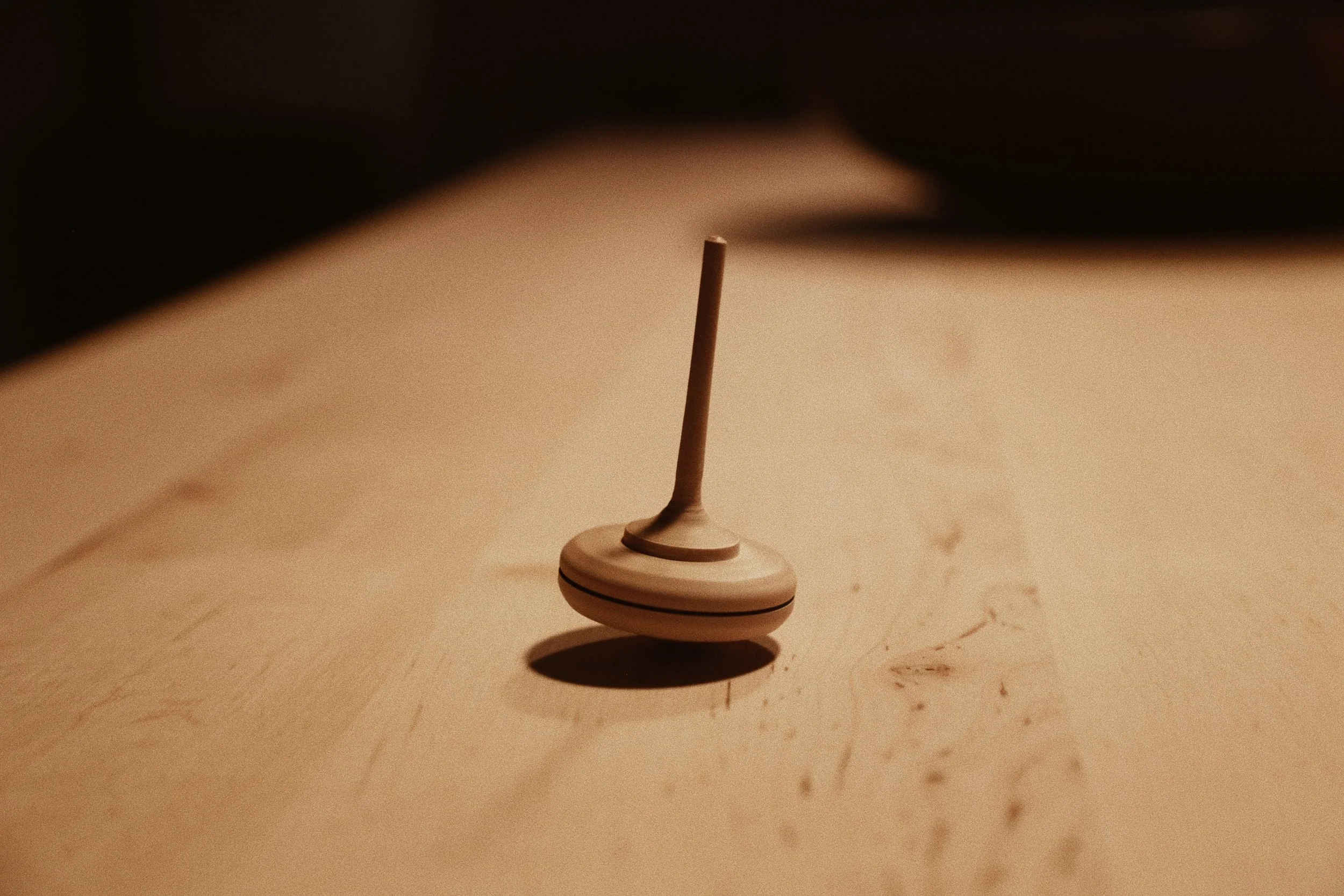 Spielzeug-Dreidel auf einem Holztisch mit Schatten