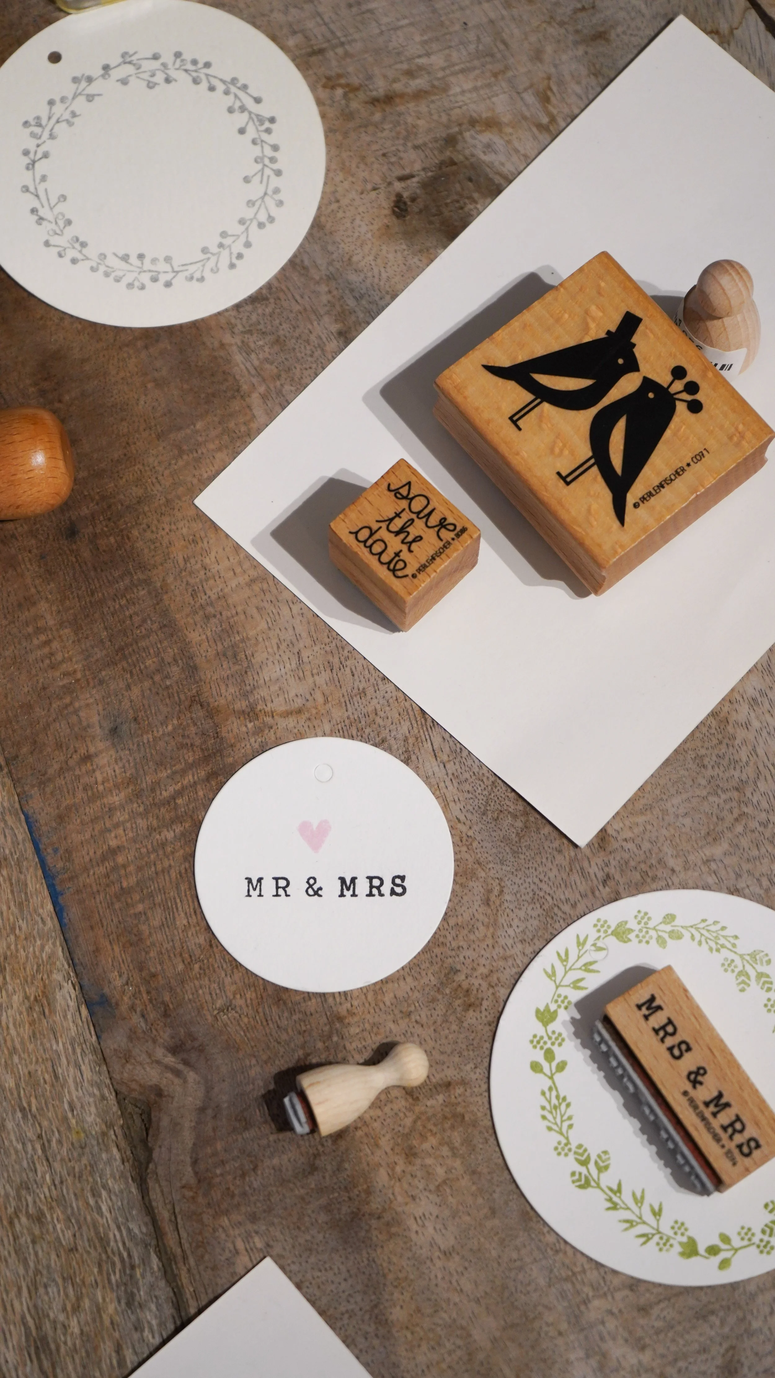 Stempel mit Hochzeitssprüchen und Namen, darunter Kärtchen mit ‚Mr & Mrs‘, auf Holztisch.