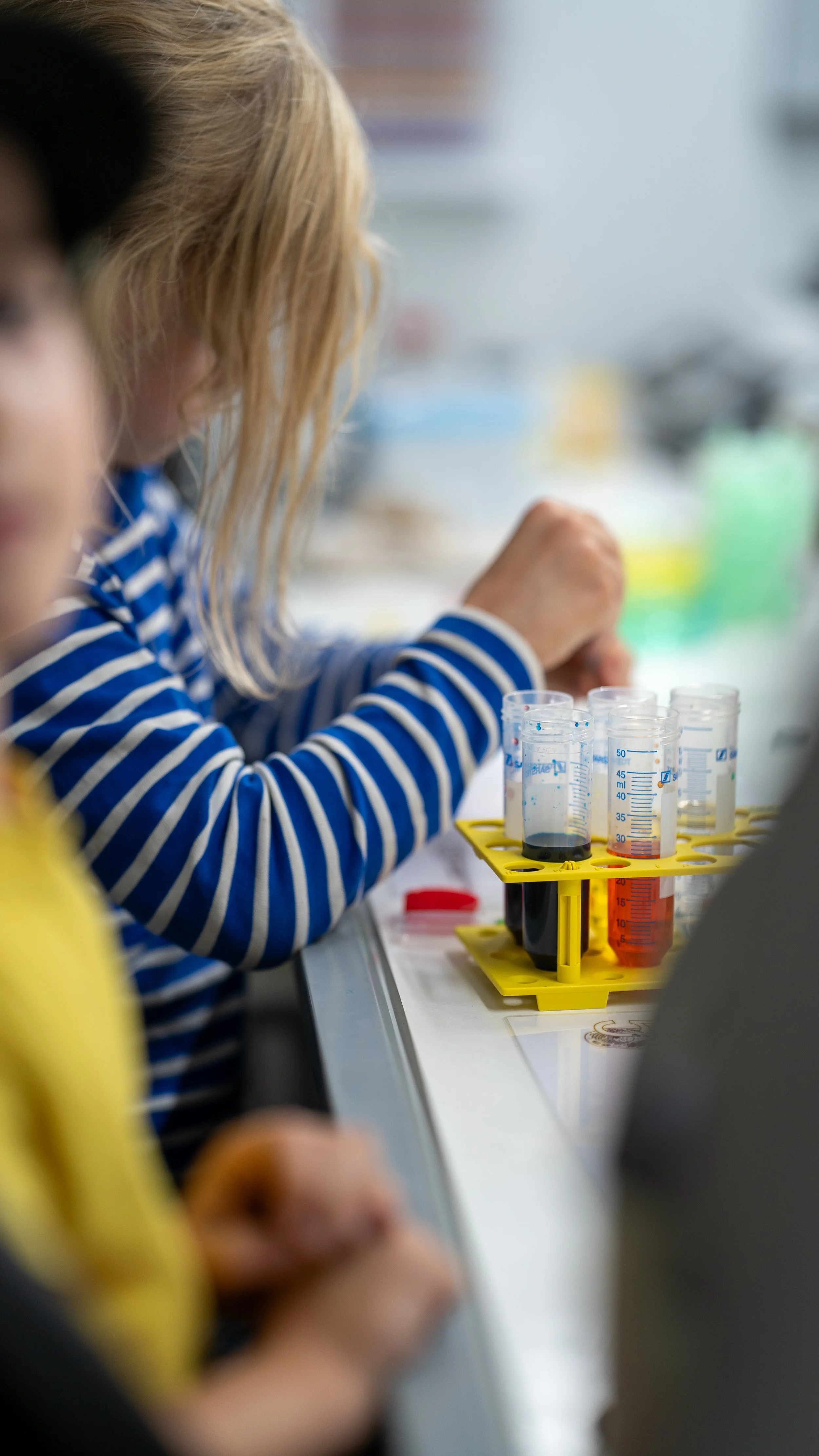 Kinder experimentieren im Labor mit Flüssigkeiten in Messbechern.