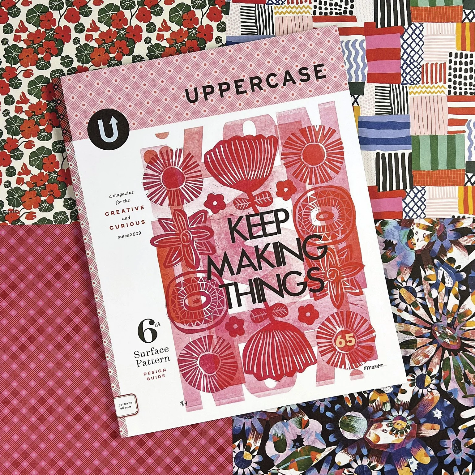 an uppercase magazine sits on top of 4 patterend papers, one of which was designed by Renee Stramel, a floral design in purples, blues and oranges.