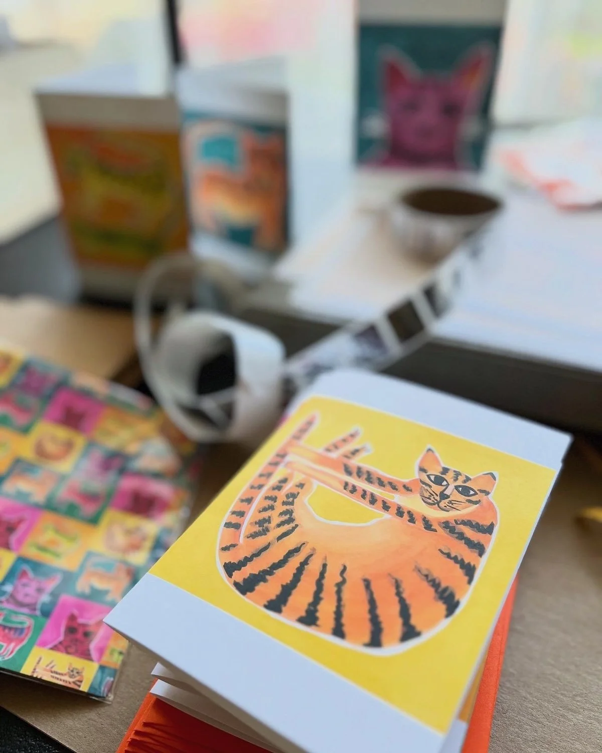 A Tiger Cat greeting Card awaits packaging with other cards on a modern desk.