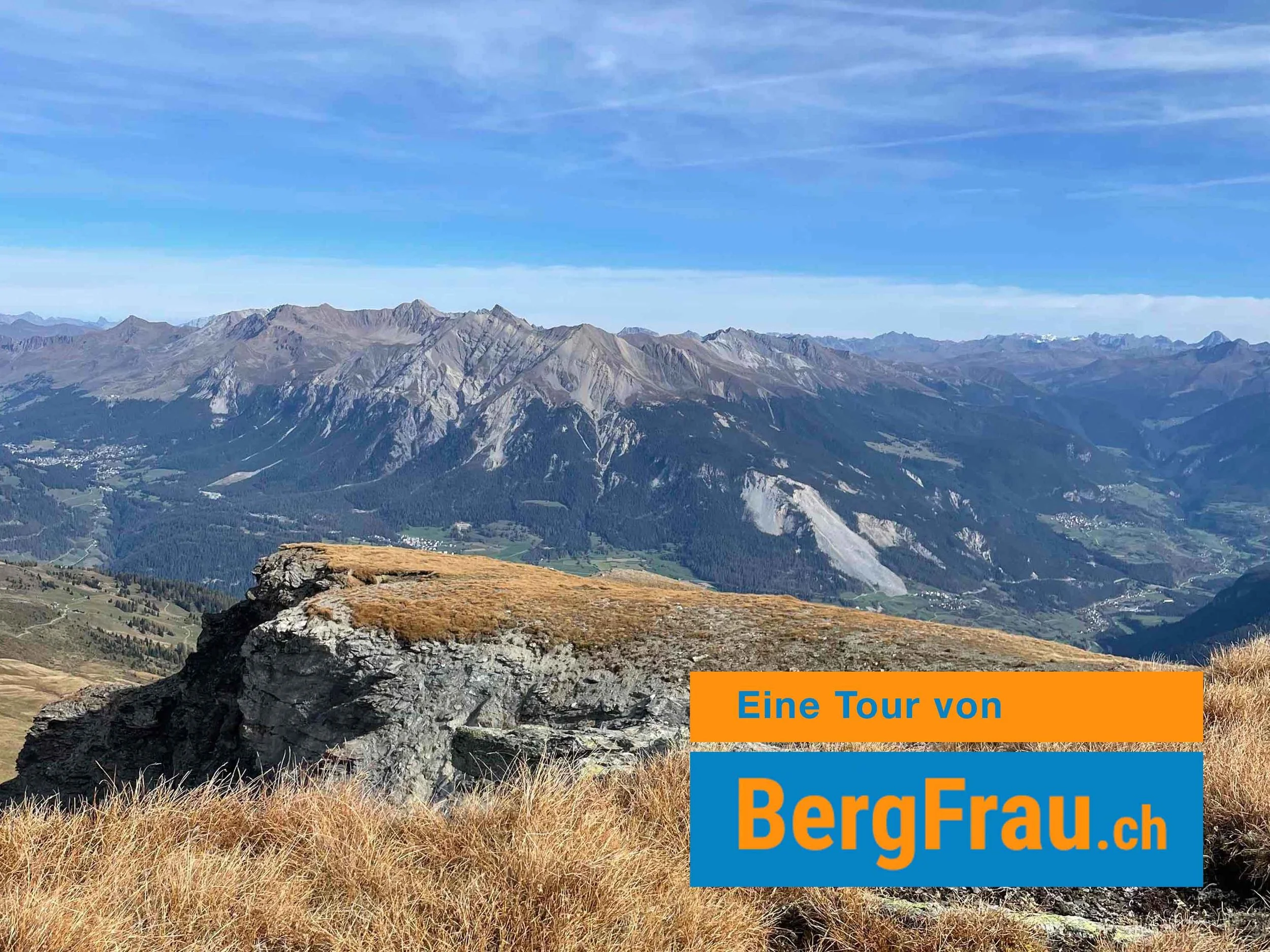 Berglandschaft mit Bergen, Gras und Felsen, blauer Himmel, Text ‚Eine Tour von BergFrau.ch‘ auf einem blauen und orangen Balken
