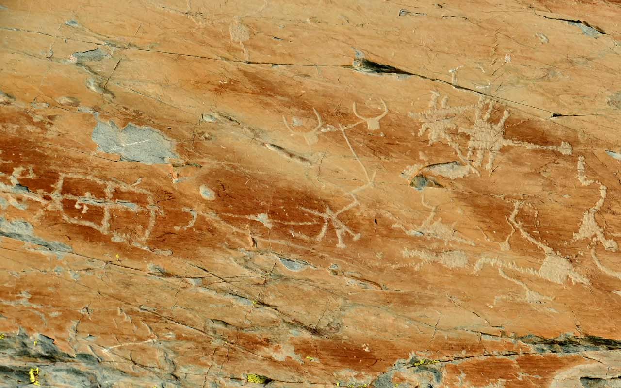 Felsen mit uralten Petroglyphen, darunter Tier- und Handsymbole.