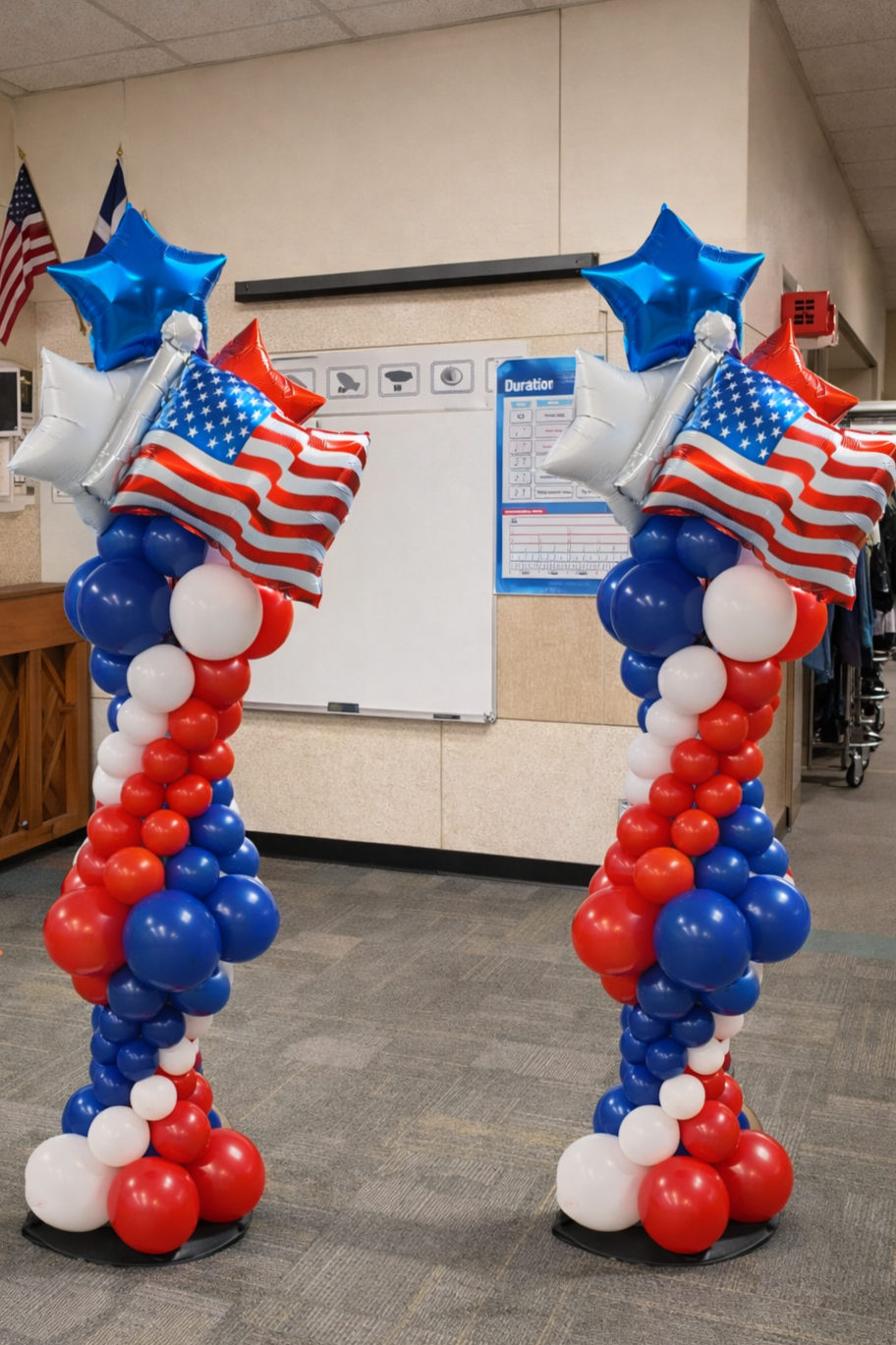Patriotic red, white, and blue balloon columns with star and American flag balloons installed indoors for a school event celebration.