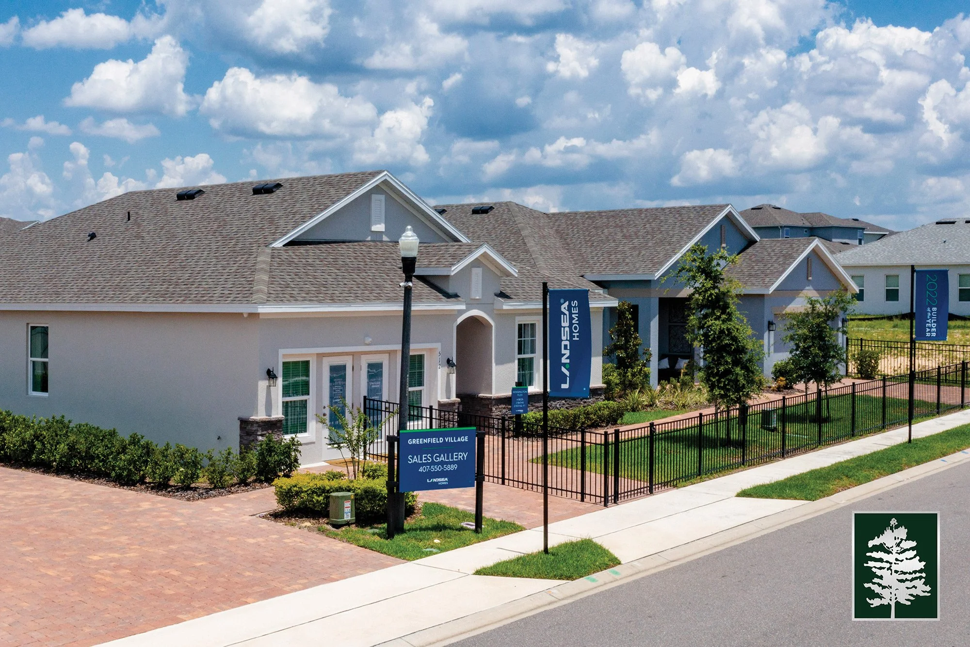 New residential houses with a sales gallery sign and fences, under partly cloudy sky.