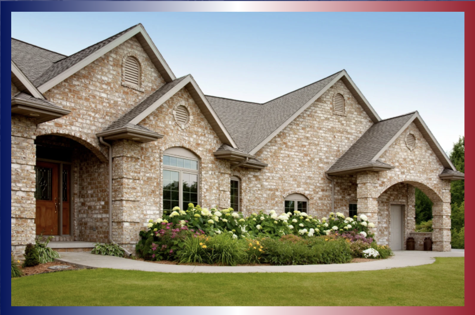 A brick house with arched windows and a landscaped front yard with flowers and green grass.