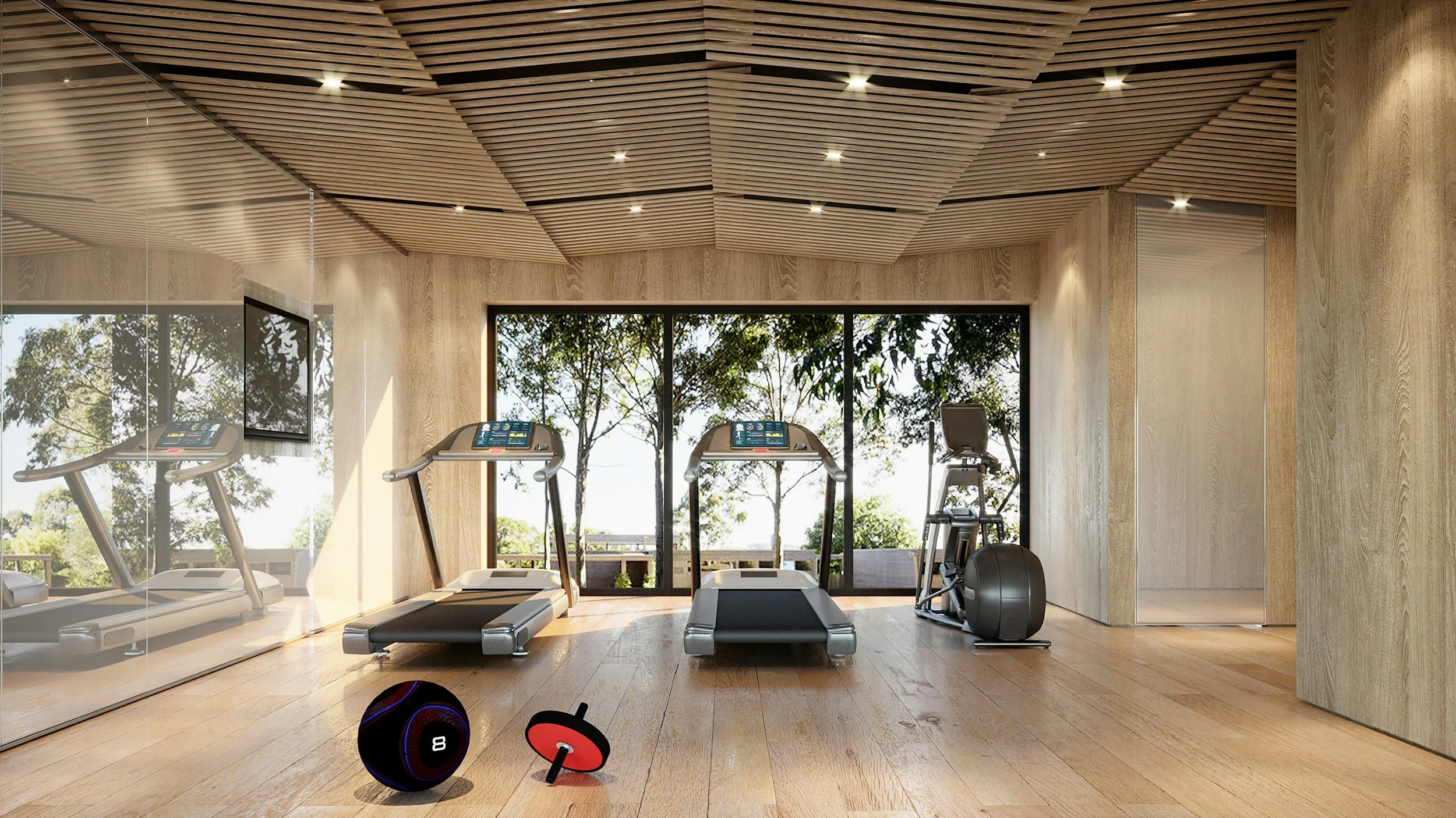 A modern gym room with wooden flooring, large glass windows showing trees outside, and ceiling with wooden slats. Includes two treadmills, a stationary bike, a fitness ball, and small weights.