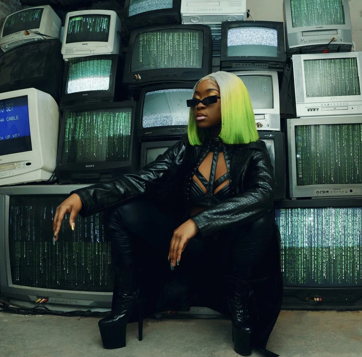 Model posing in front of stacked CRT televisions with Matrix video display at Gymnopedie