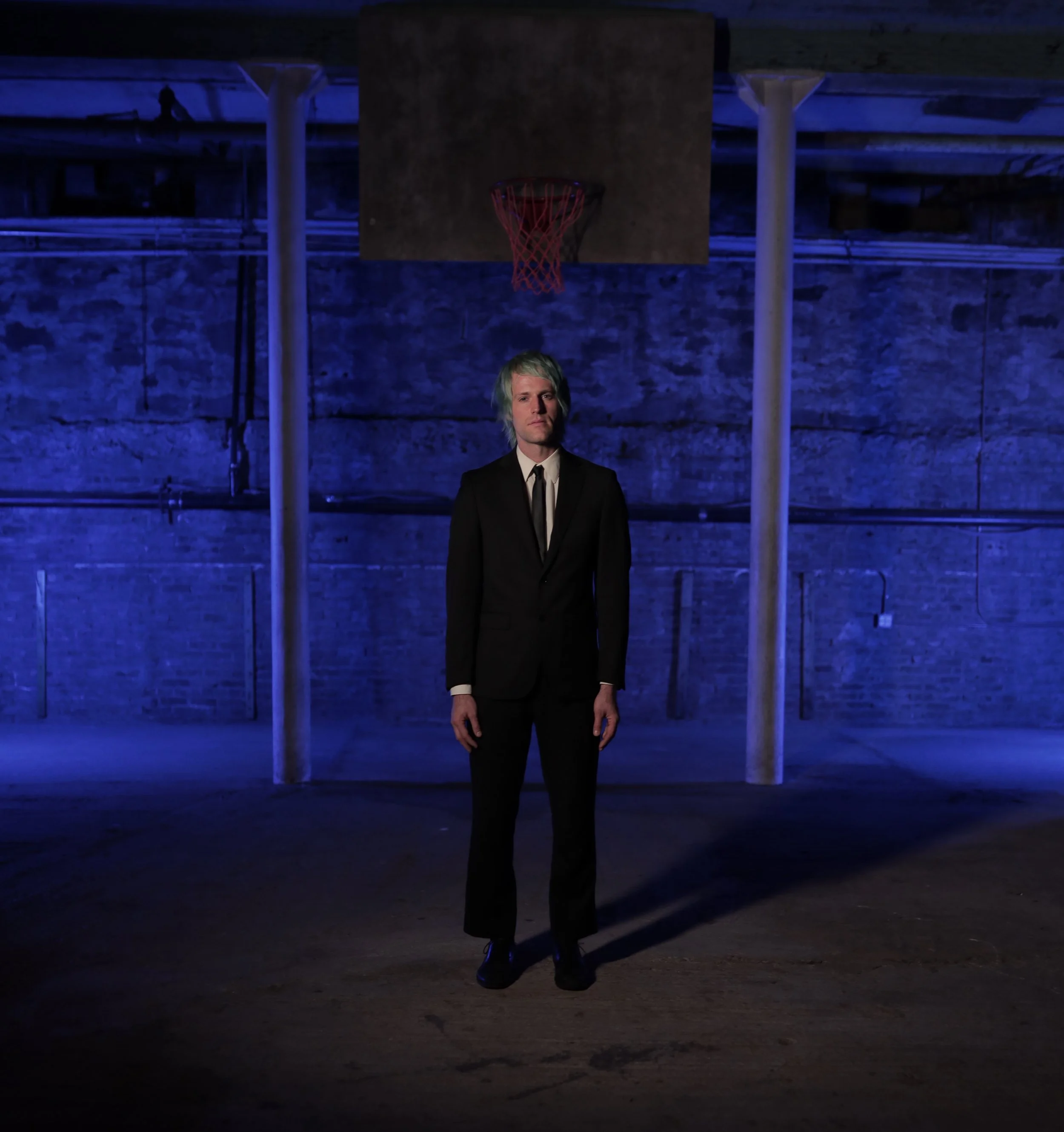 Artistic director Andrew Hoepfner standing in blue-lit gymnasium at Gymnopedie