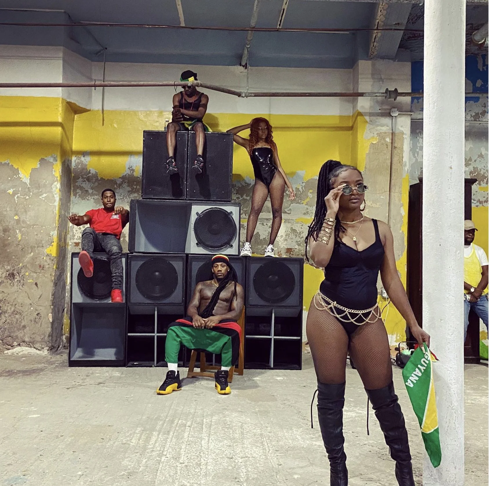 Guyanese music video extras posing in front of a stacked speaker system in the Gymnopedie gymnasium