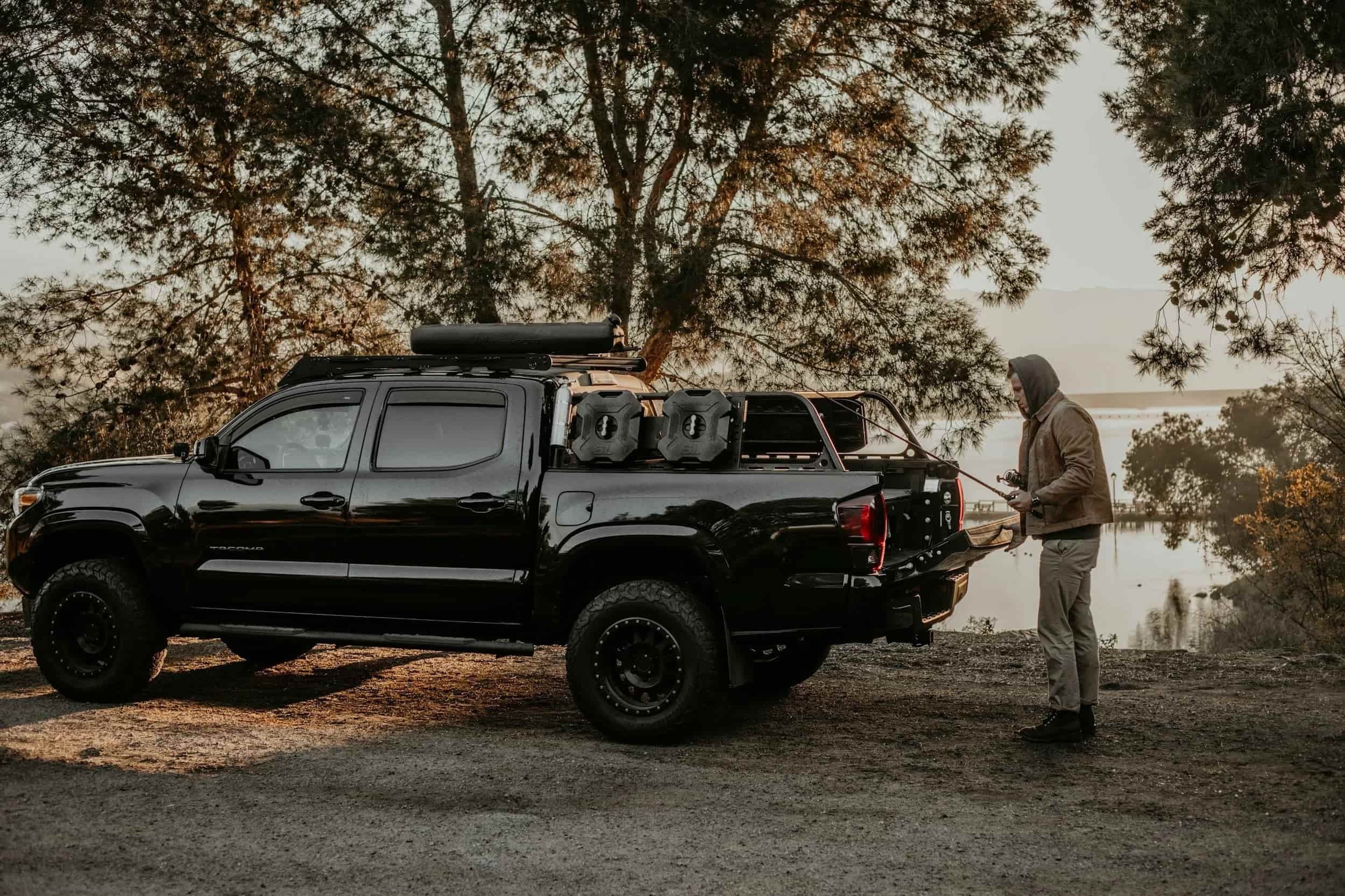 Fisherman at the back of his overland vehicle with fishing gear and racks