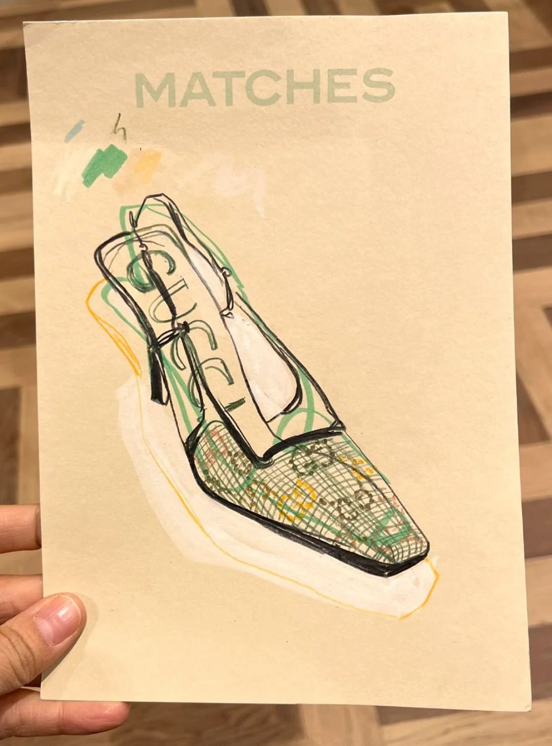 Sketch of a patterned high-heeled shoe on a beige background with the word 'MATCHES' at the top.