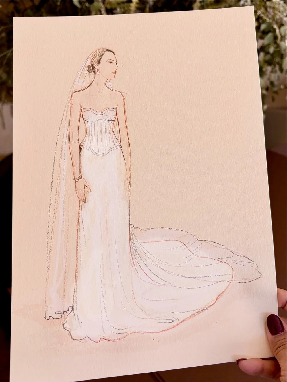 A fashion sketch of a woman in a wedding dress, with a strapless bodice, long train, and veil, drawn with light colored lines.