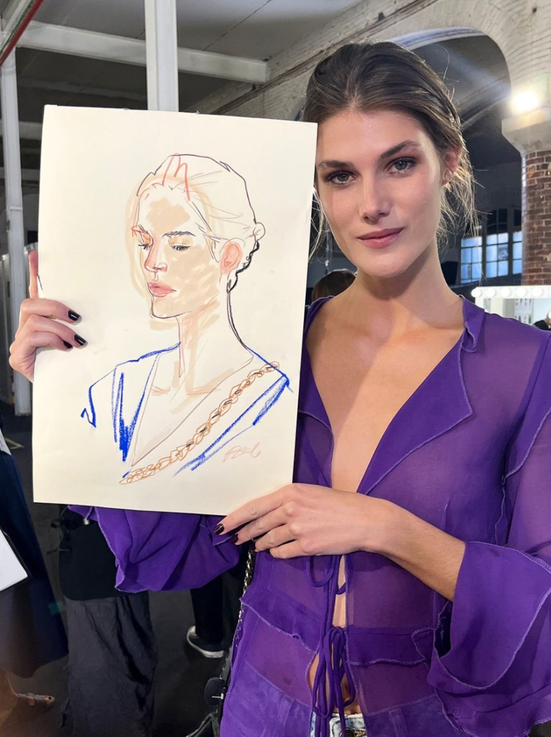A woman in a purple outfit holding a drawing of herself.