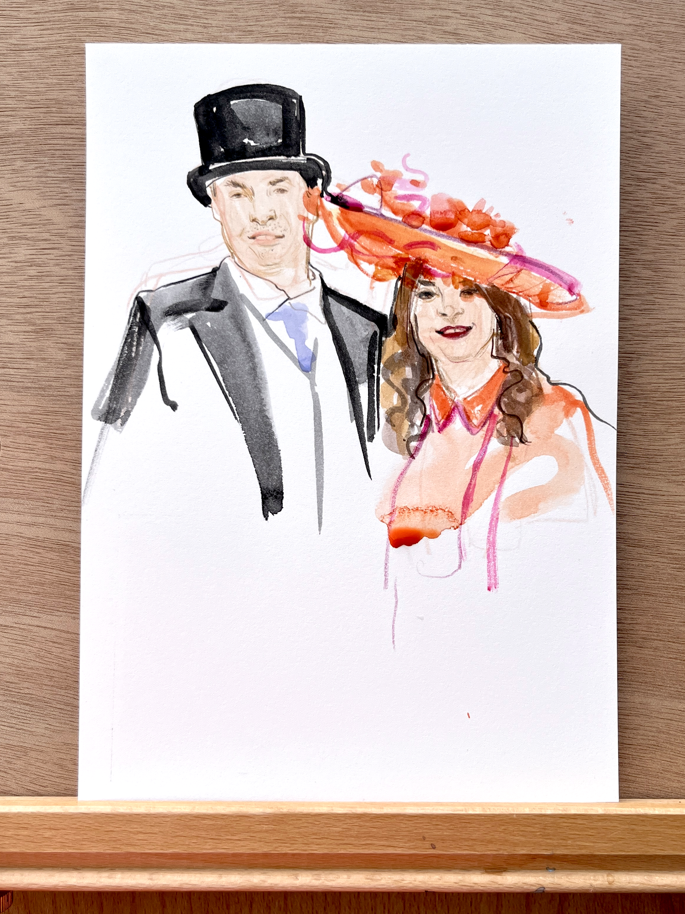 Watercolor painting of a man in a tuxedo with a top hat and a woman in a peach-colored outfit with a large, elaborate orange hat, on white paper with a wooden background.