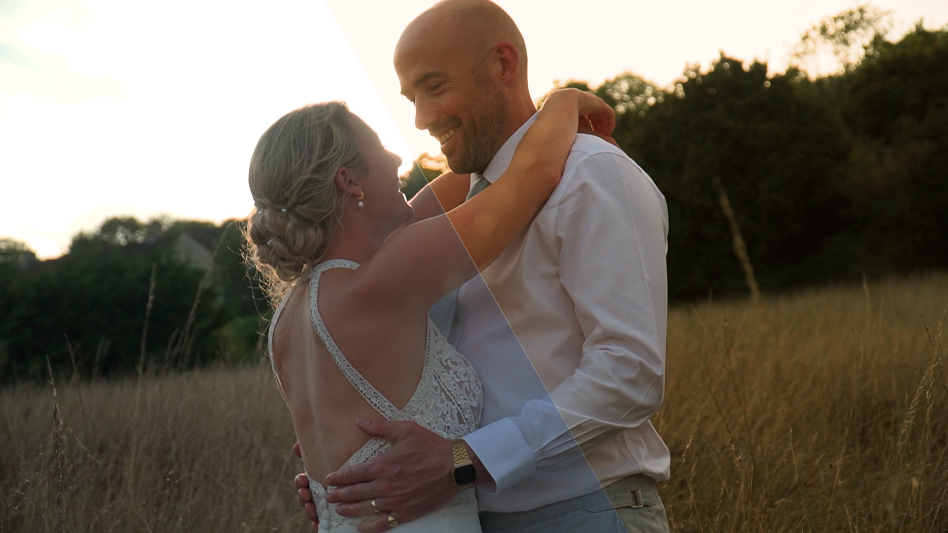 married couple holding each other in a long grass field