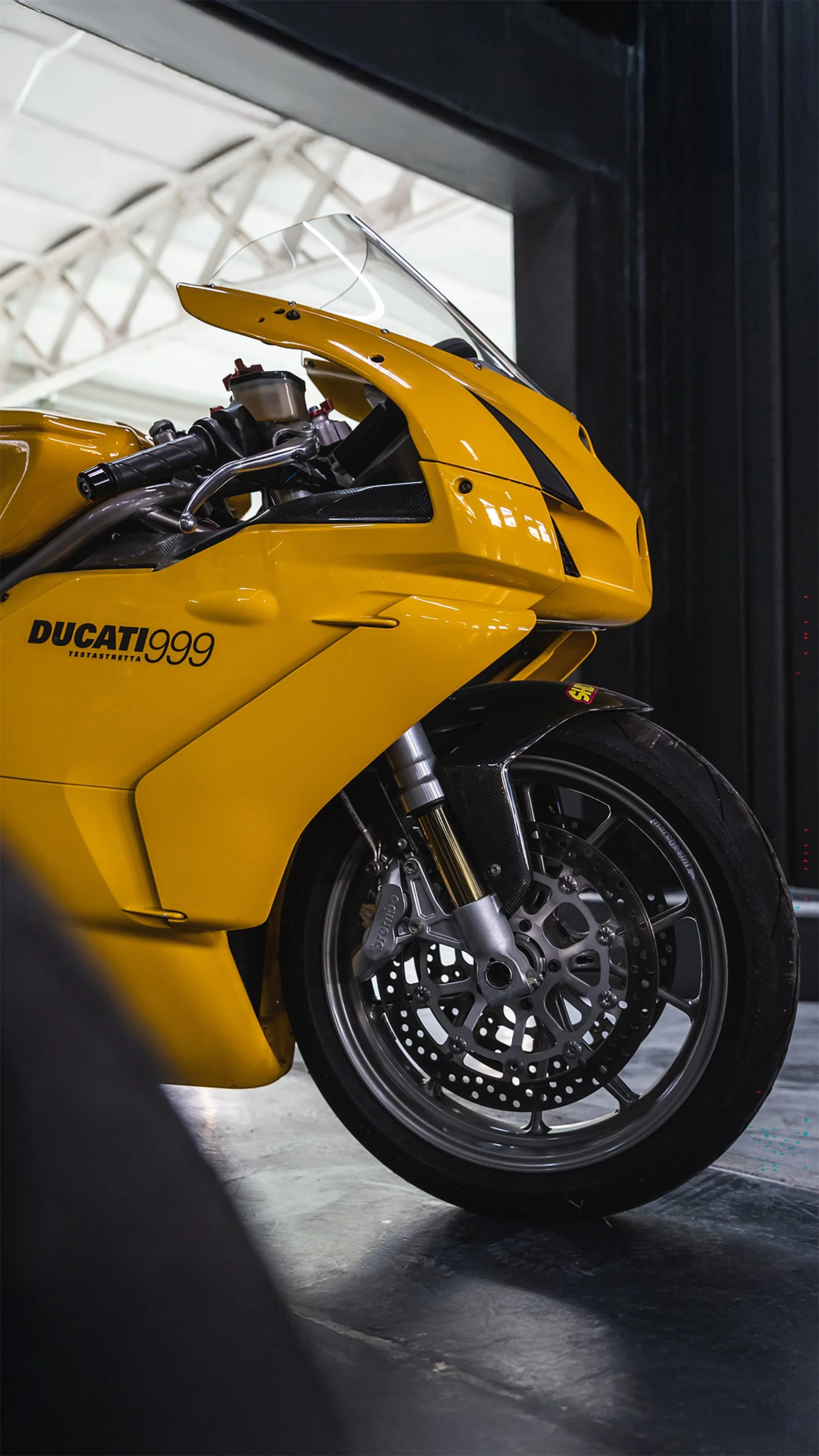 Motocicletta sportiva gialla Ducati 999 nel garage, vista laterale con ruote e parte del cupolino