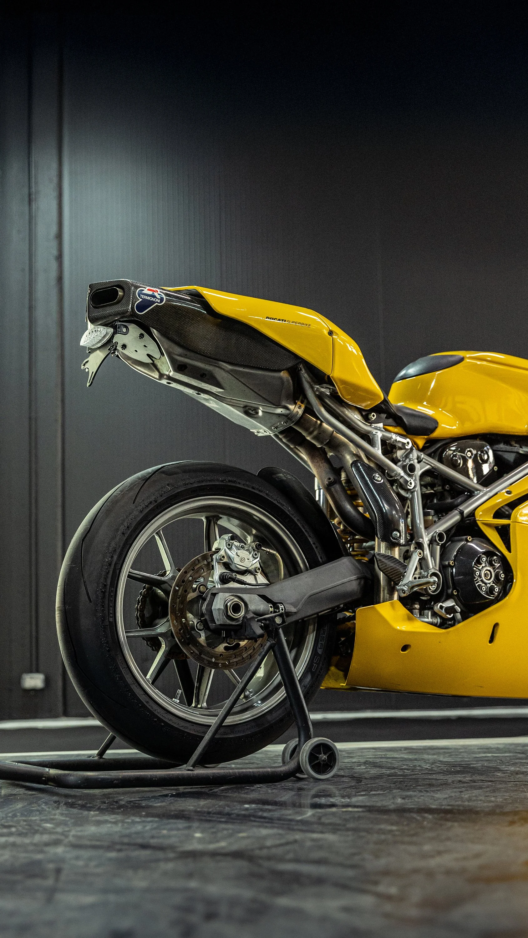 Moto racing gialla su supporto, visibile la ruota posteriore e parte del telaio.