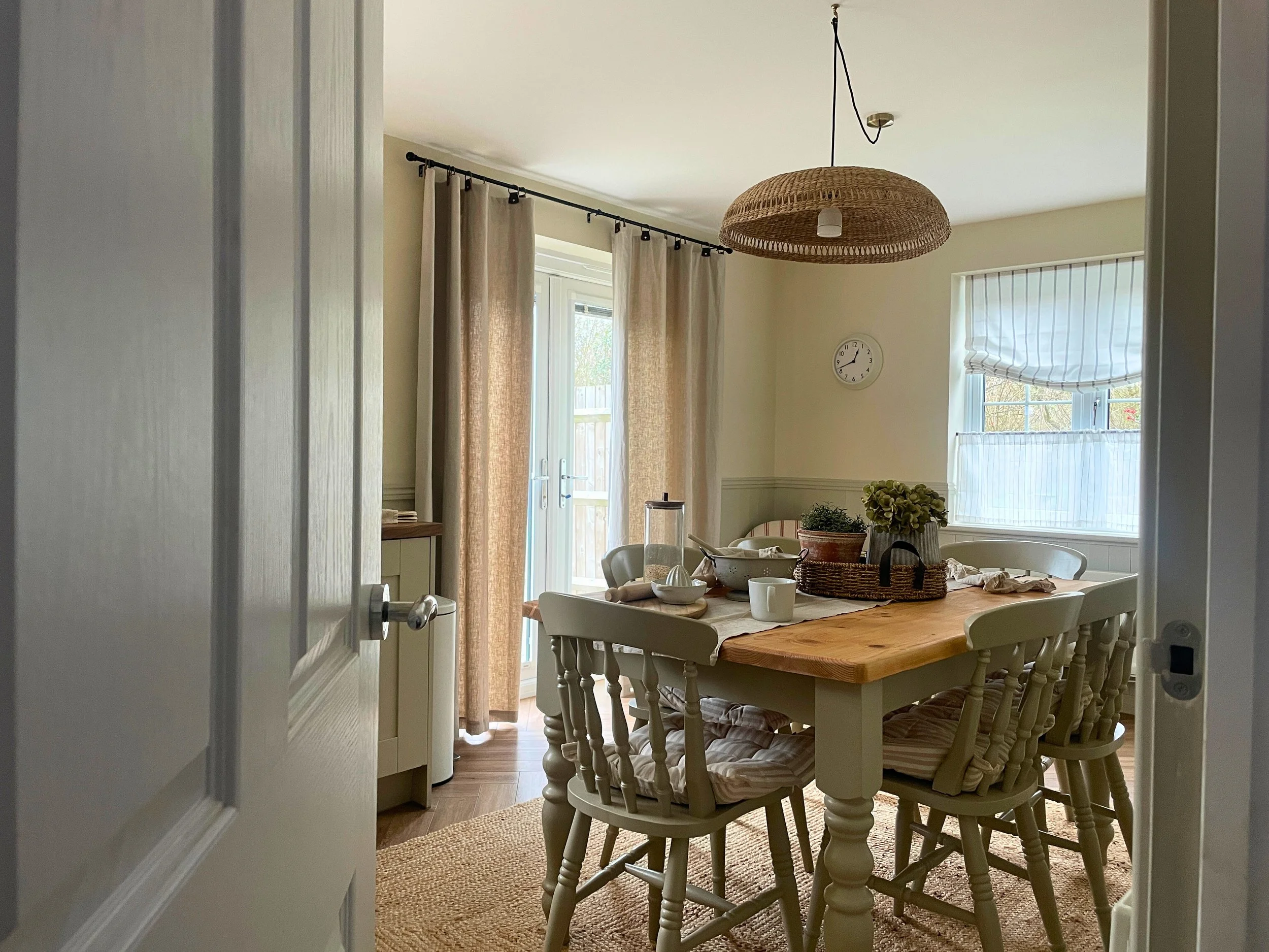 Farmhouse dining room with wooden table, rattan pendant and a window seat