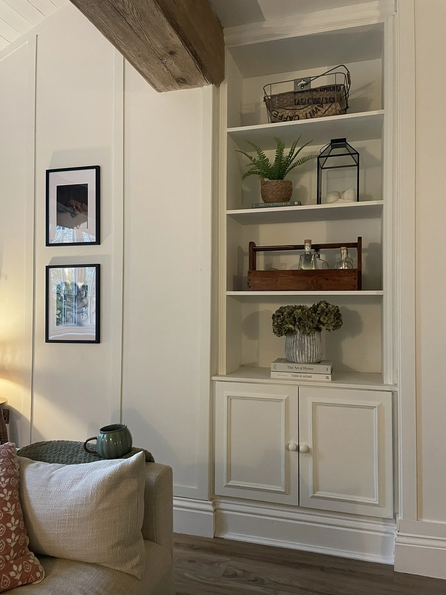 Cream built-in shelving nook with framed prints and woven baskets