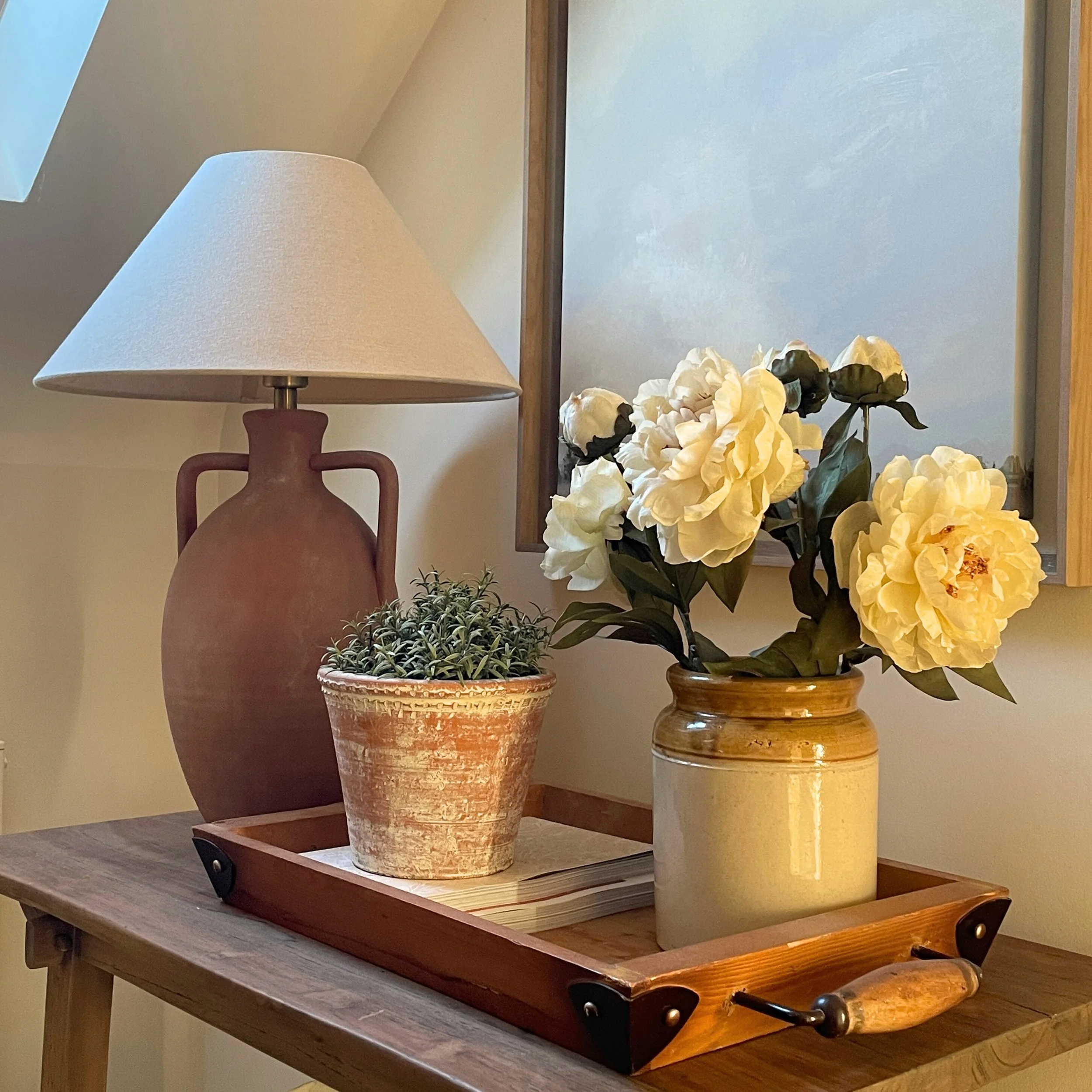 Console table styled with a lamp, terracotta pot and yellow roses